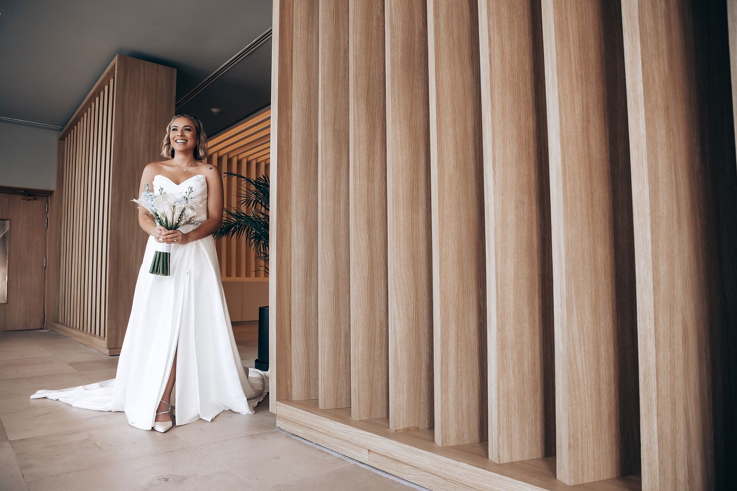 Wedding party posing against wooden paneled wall in elegant venue.