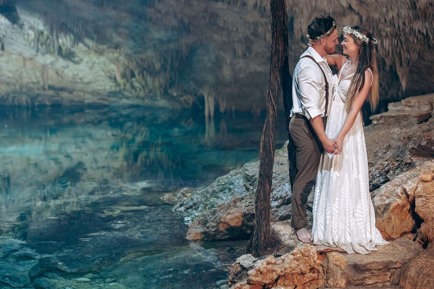 People enjoying a serene moment at the edge of a crystal-clear cenote surrounded by limestone walls.