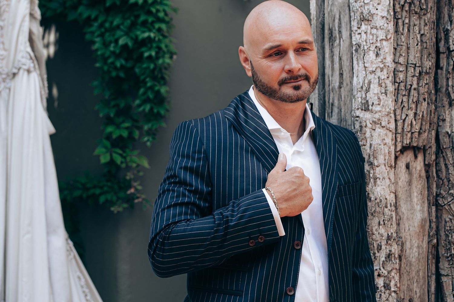 Professional portraits showing someone in a pinstripe suit against a textured gray background.