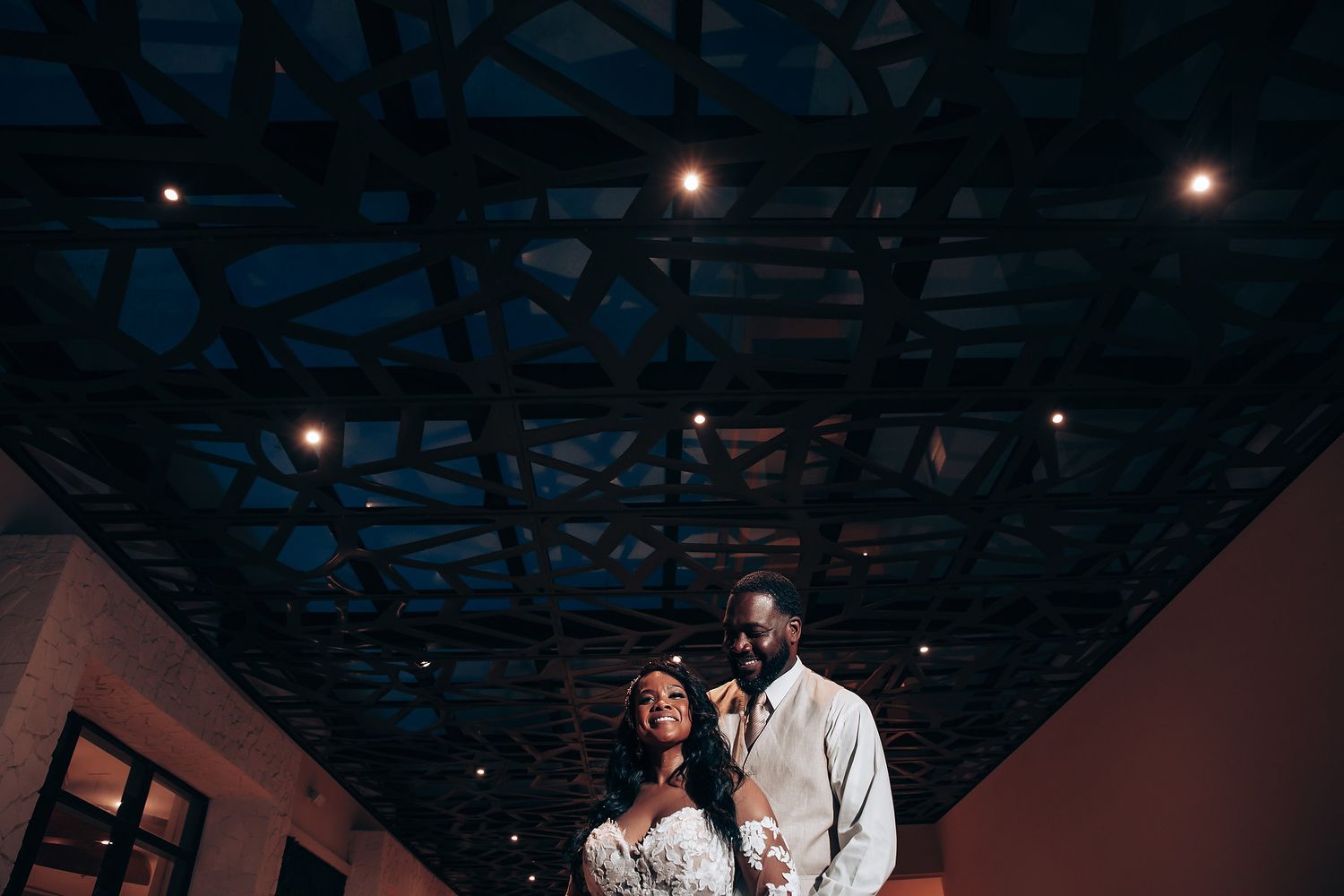 Romantic wedding couple dancing under moody lighting at evening reception.