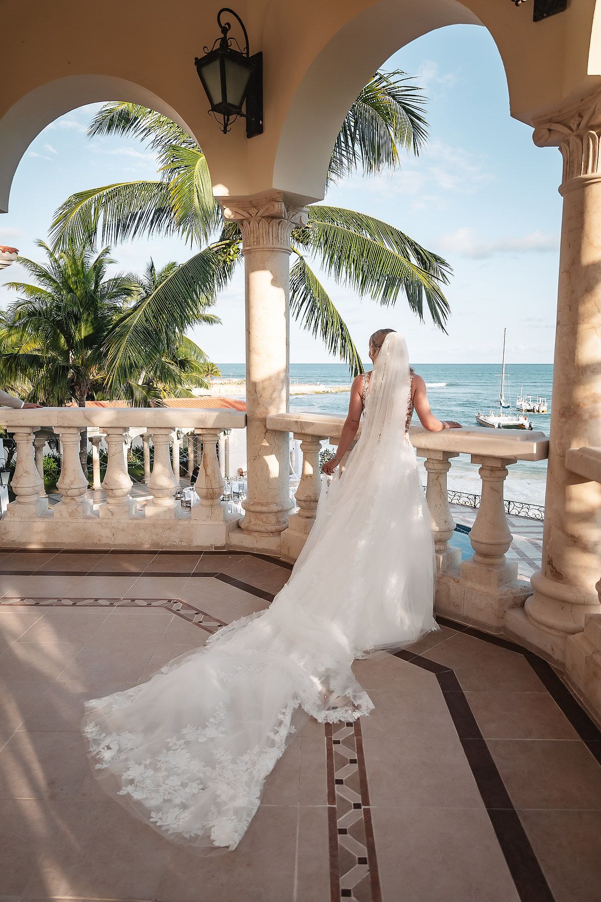 Beachfront wedding portrait on a tropical terrace with palm trees and ocean views.