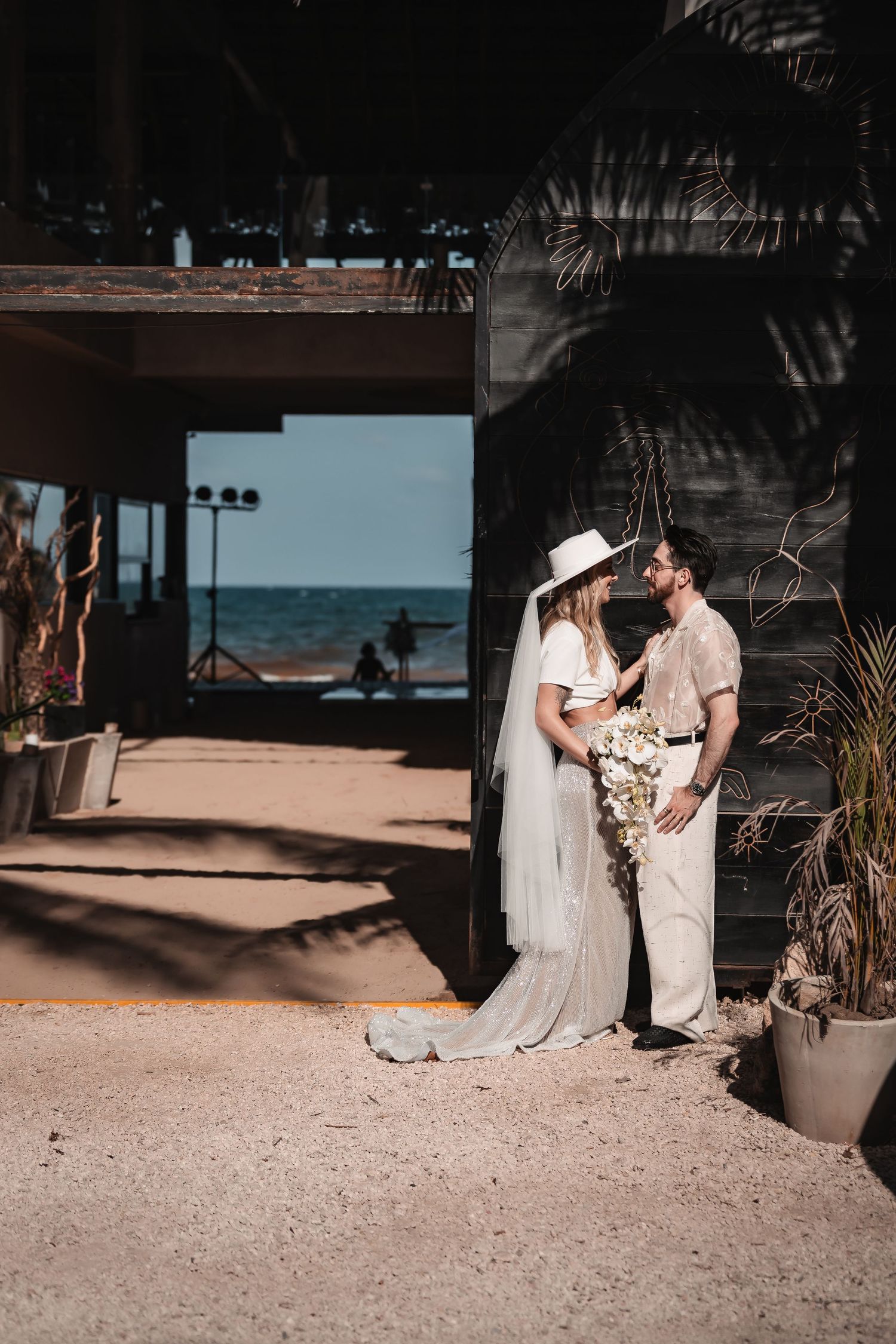Beach wedding sequence with couple posing under covered oceanfront setting.
