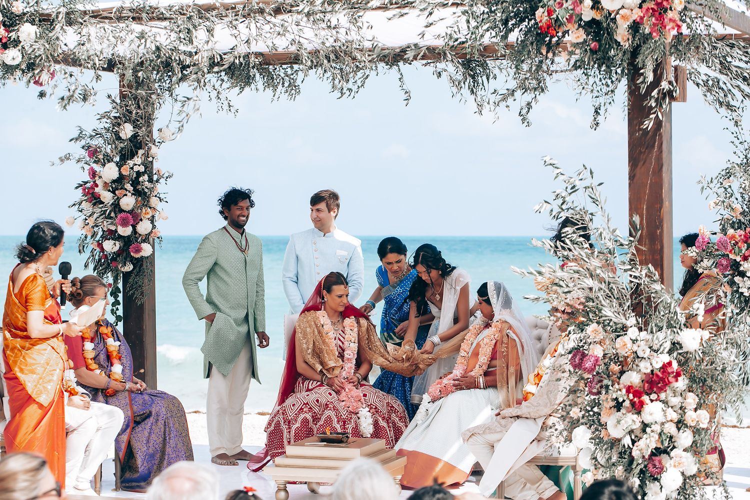 Panoramic view of a beach wedding setup with white and floral decorations against blue waters.