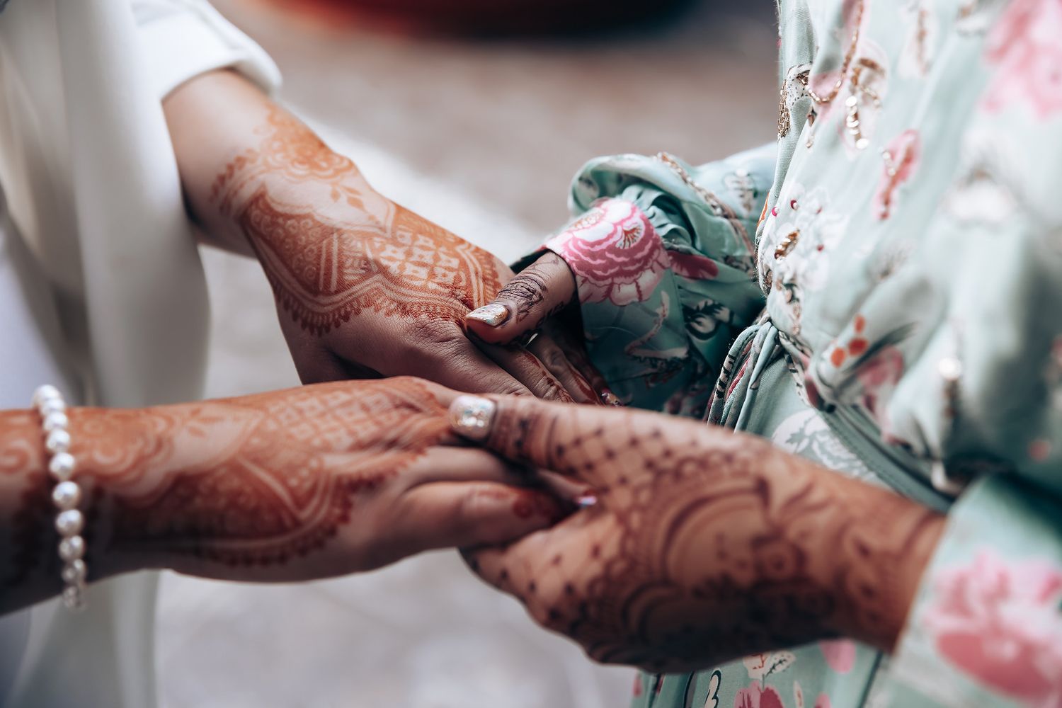 Close-up of hands with intricate henna designs exchanging traditional wedding items.