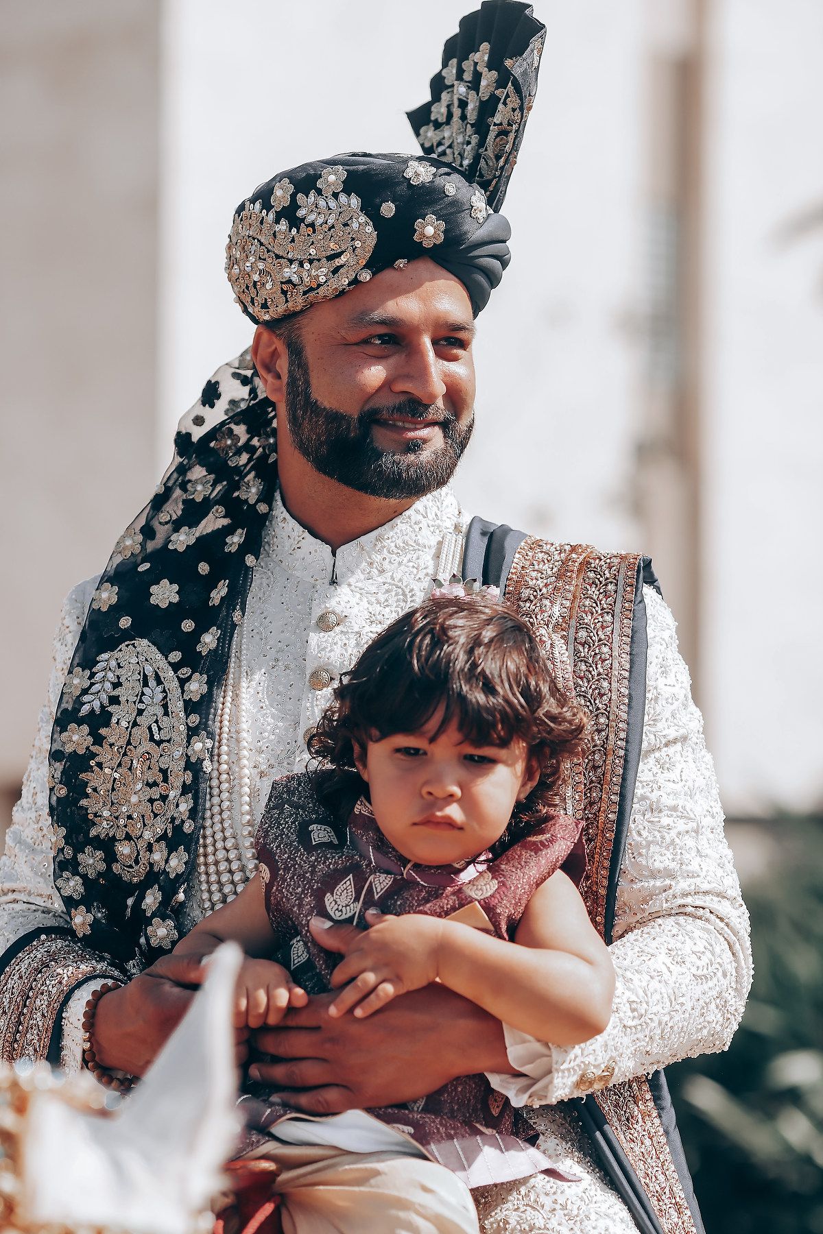 Traditional South Asian wedding attire with ornate embroidered sherwani and turban.
