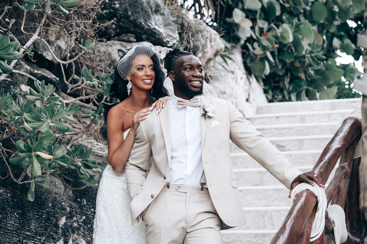 Happy couple celebrating on outdoor stairs decorated with floral arrangements.