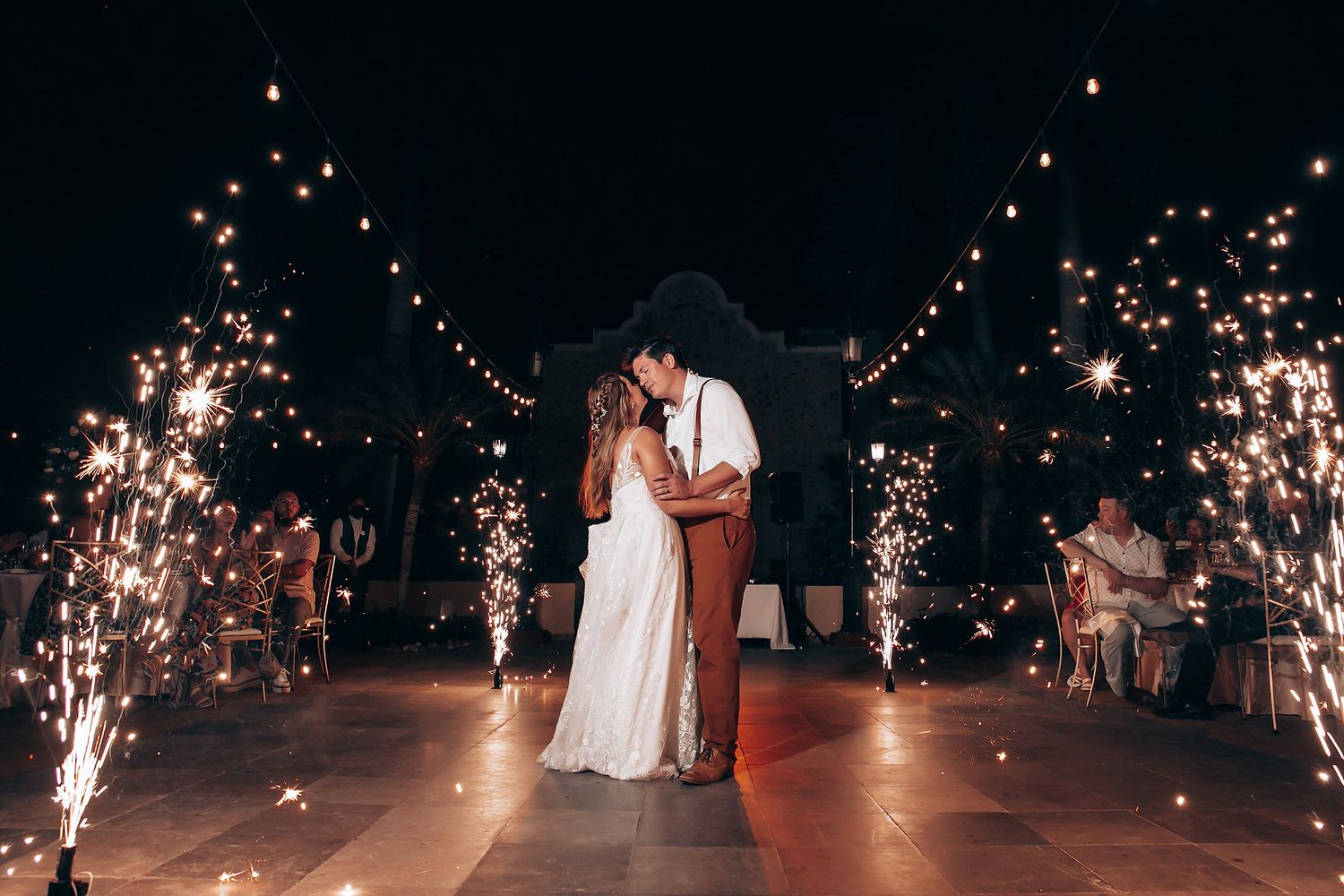Wedding celebration at night with sparklers creating magical light trails against the dark sky.