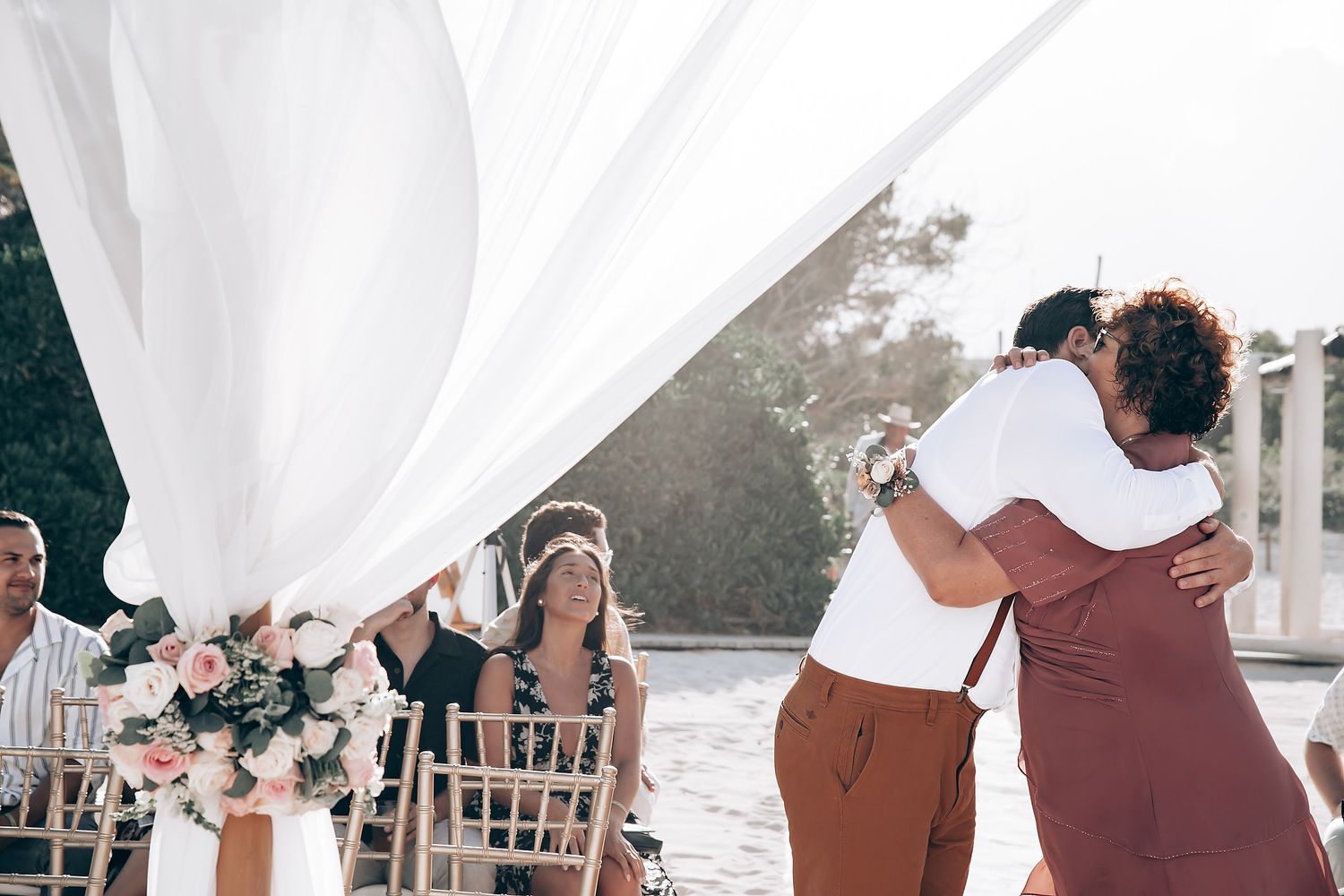 Wedding party poses outdoors in burgundy and white attire under natural lighting.