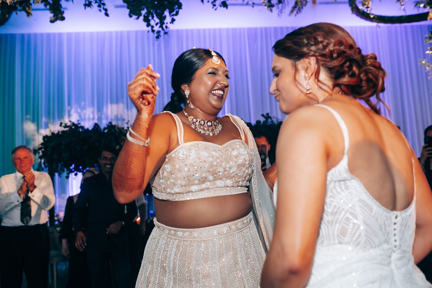 Two people sharing a lively moment on the dance floor at an elegant wedding reception.