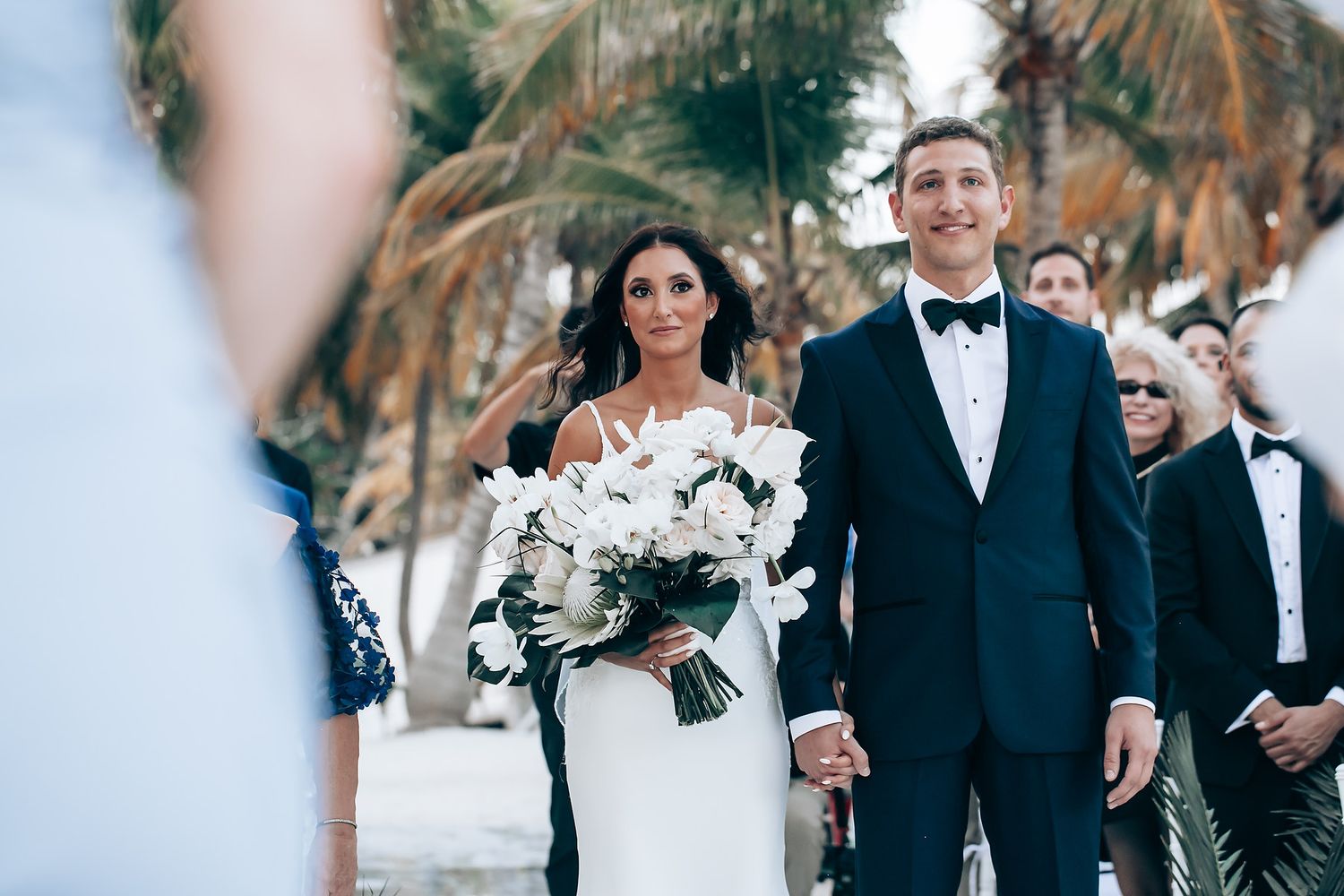 Elegant beach wedding ceremony with bridal party in formal attire.