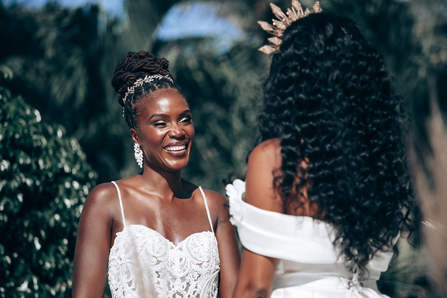 Wedding party members in white and emerald green dresses posing together outdoors.