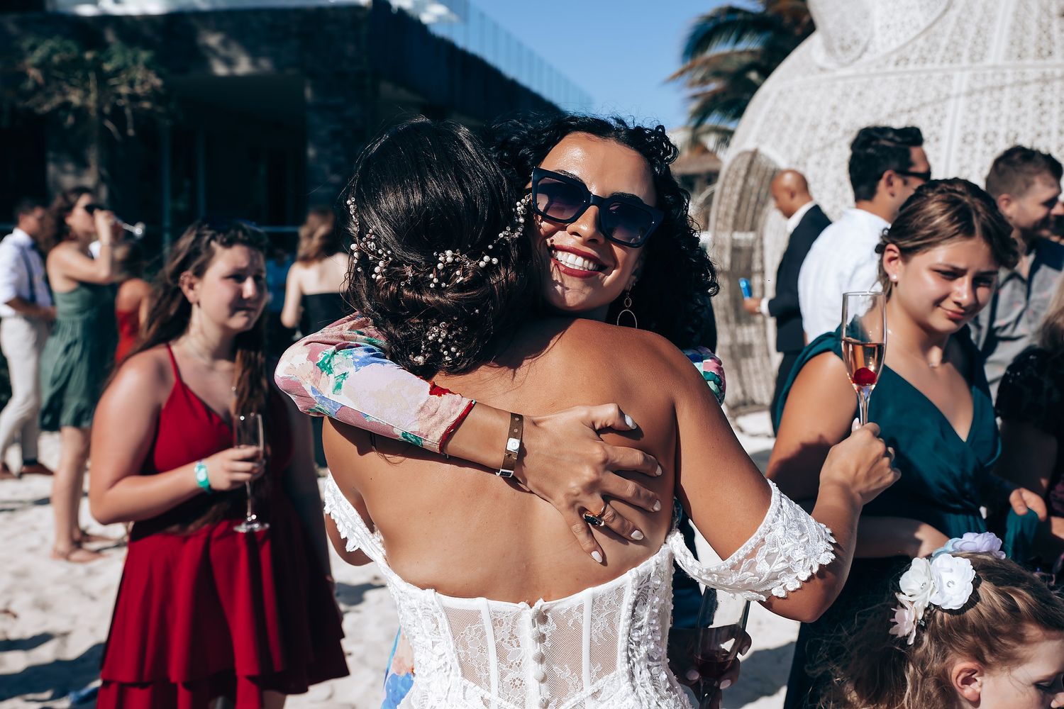 Wedding guests mingle under string lights at an outdoor tropical reception.