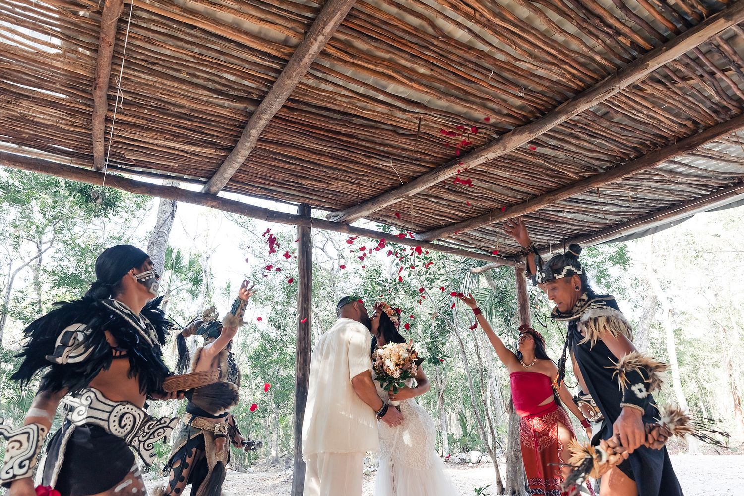 Traditional ceremony under wooden palapa roof with spiritual elements.