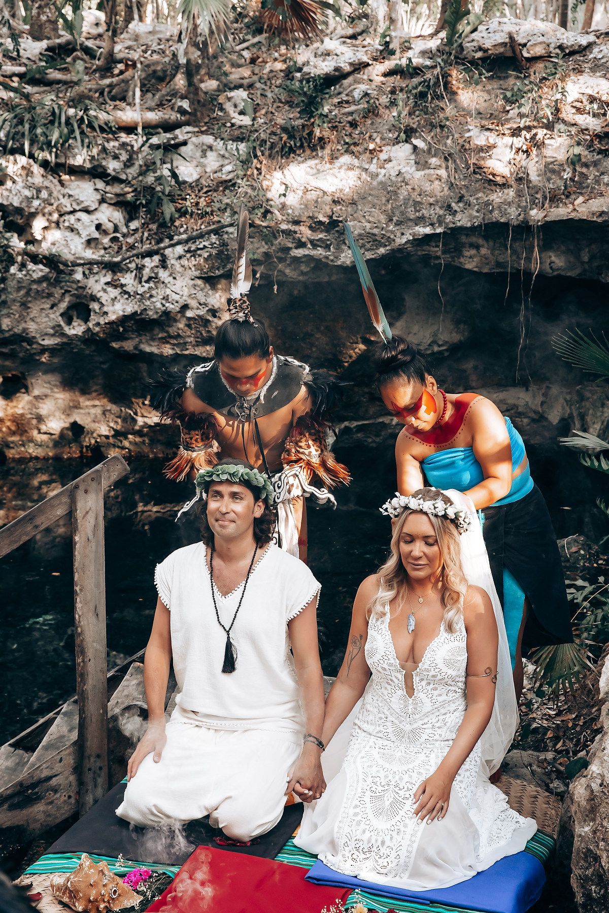 A couple in white outfits share a candid moment while sitting together in a rustic outdoor setting.
