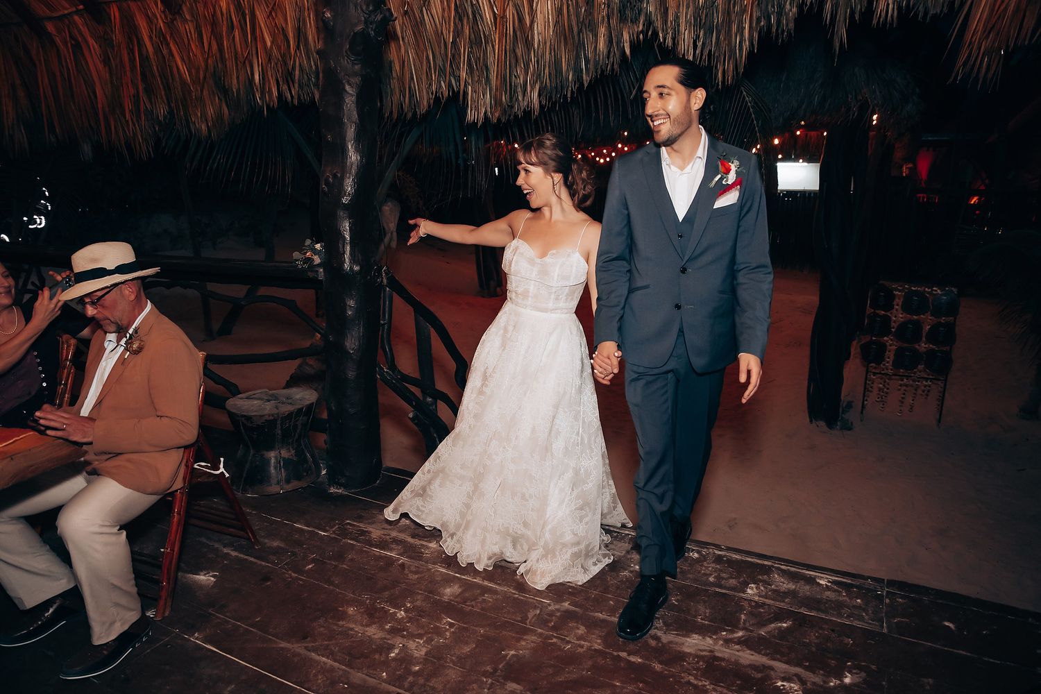 A couple dances together at a wedding reception while guests watch and take photos in a dimly lit venue.