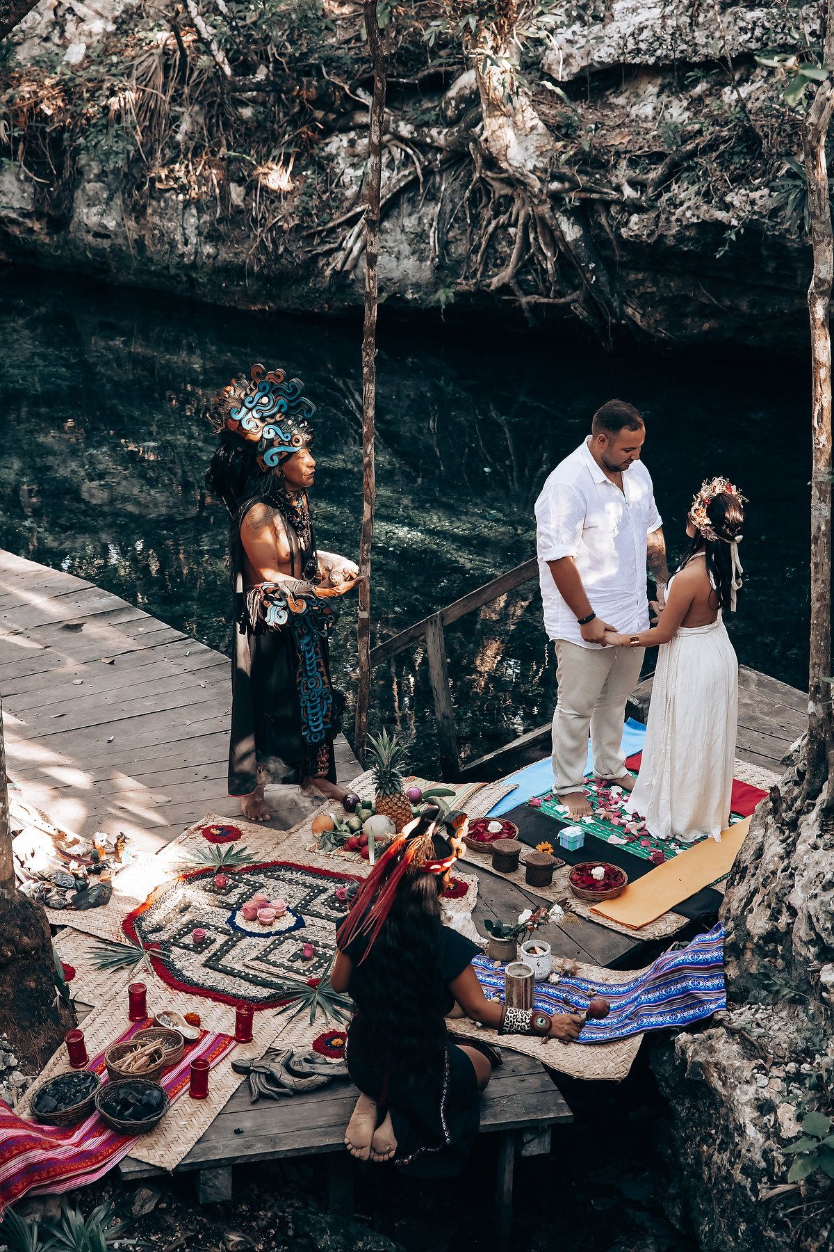 Traditional ceremony items and decorations are laid out on wooden planks against a stone wall backdrop.