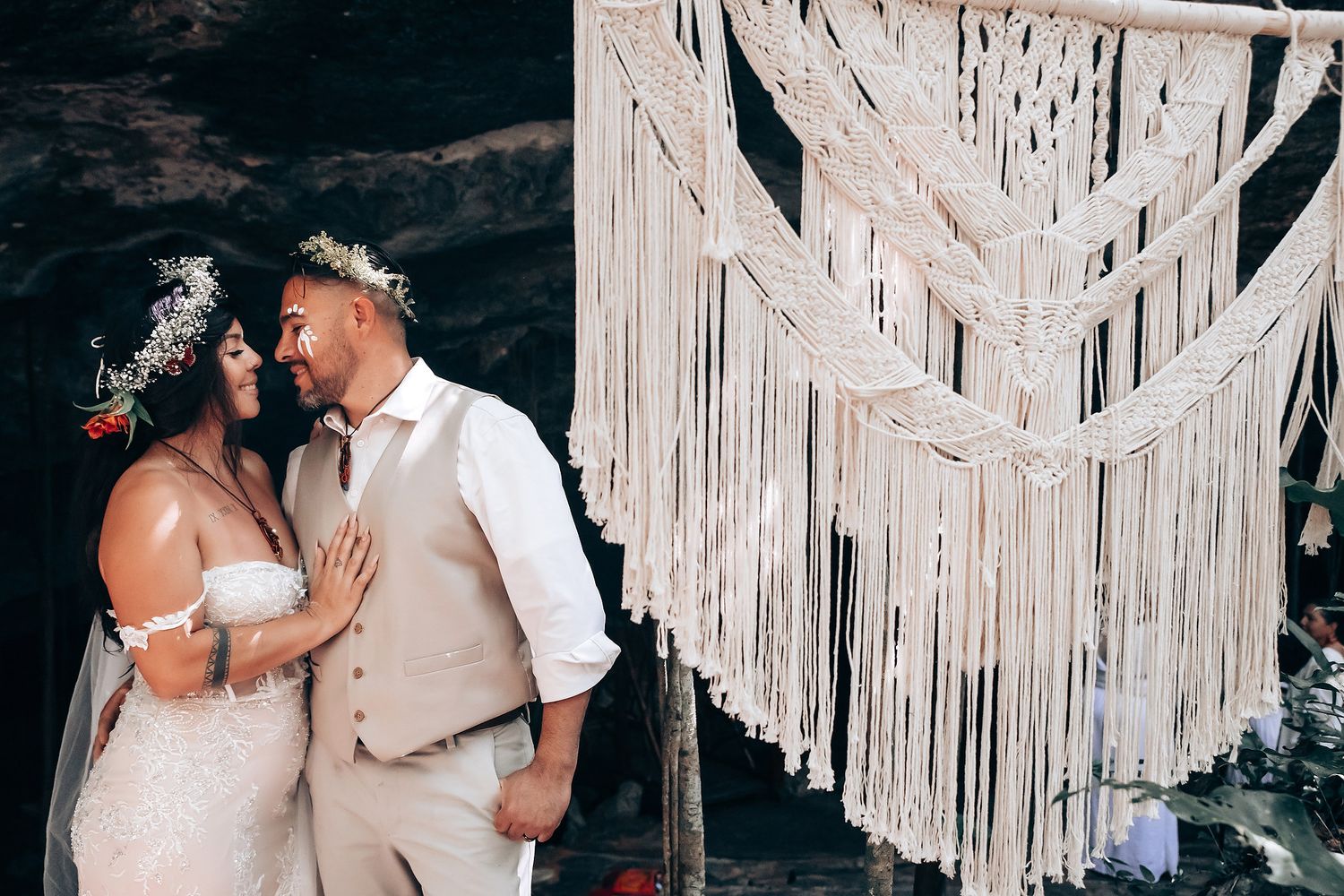 Romantic wedding ceremony in cave setting with bohemian macrame decorations.