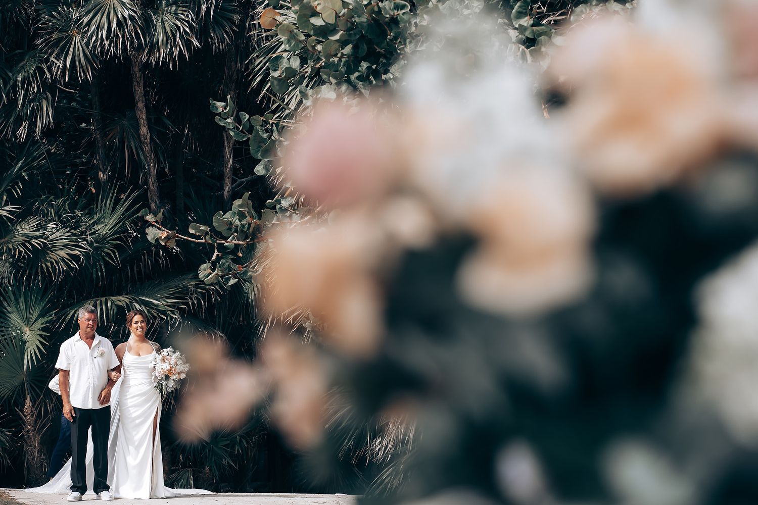 Blurred wedding scene with soft bokeh effect and tropical foliage.