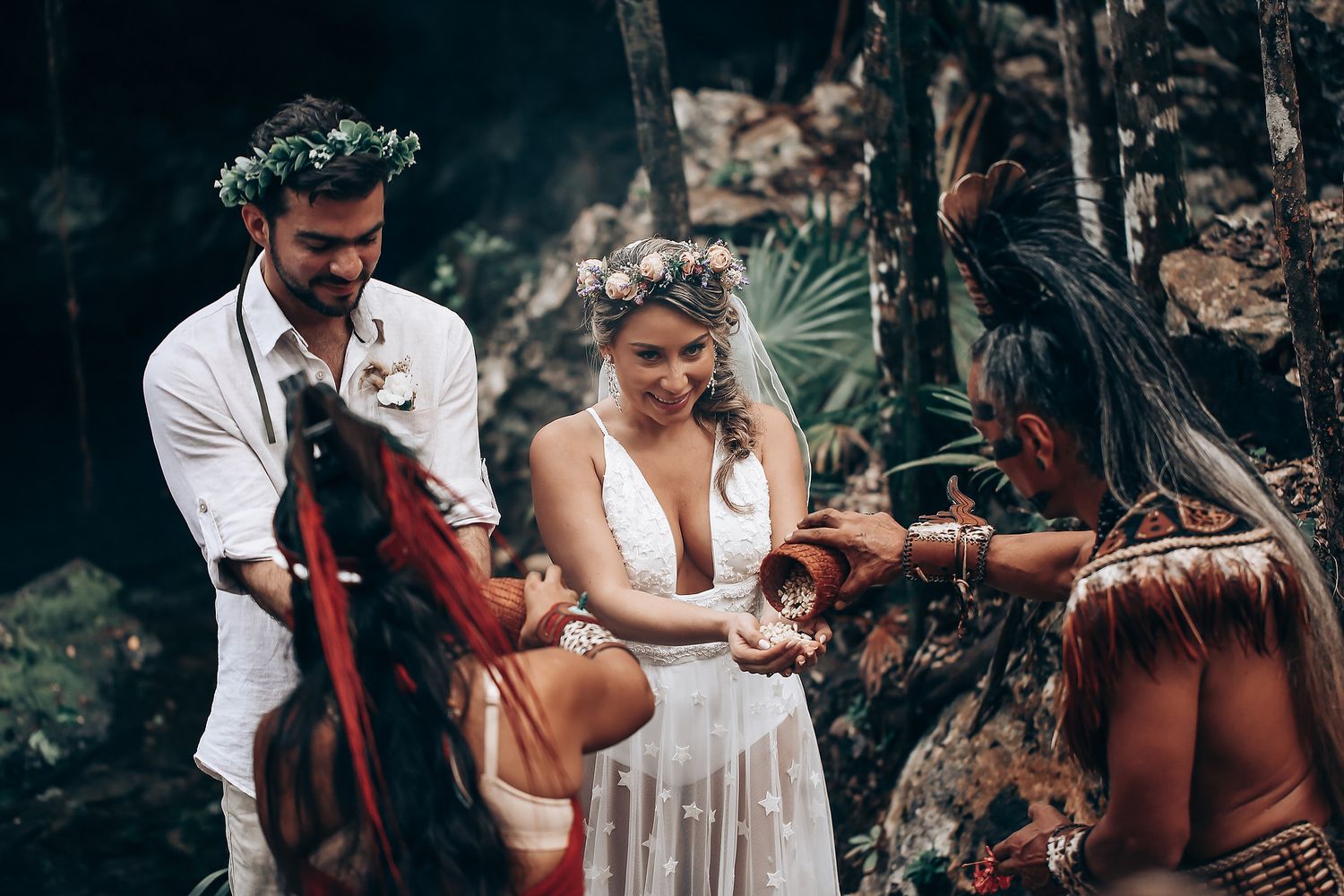 A wedding ceremony incorporates indigenous cultural traditions in a natural forest setting.