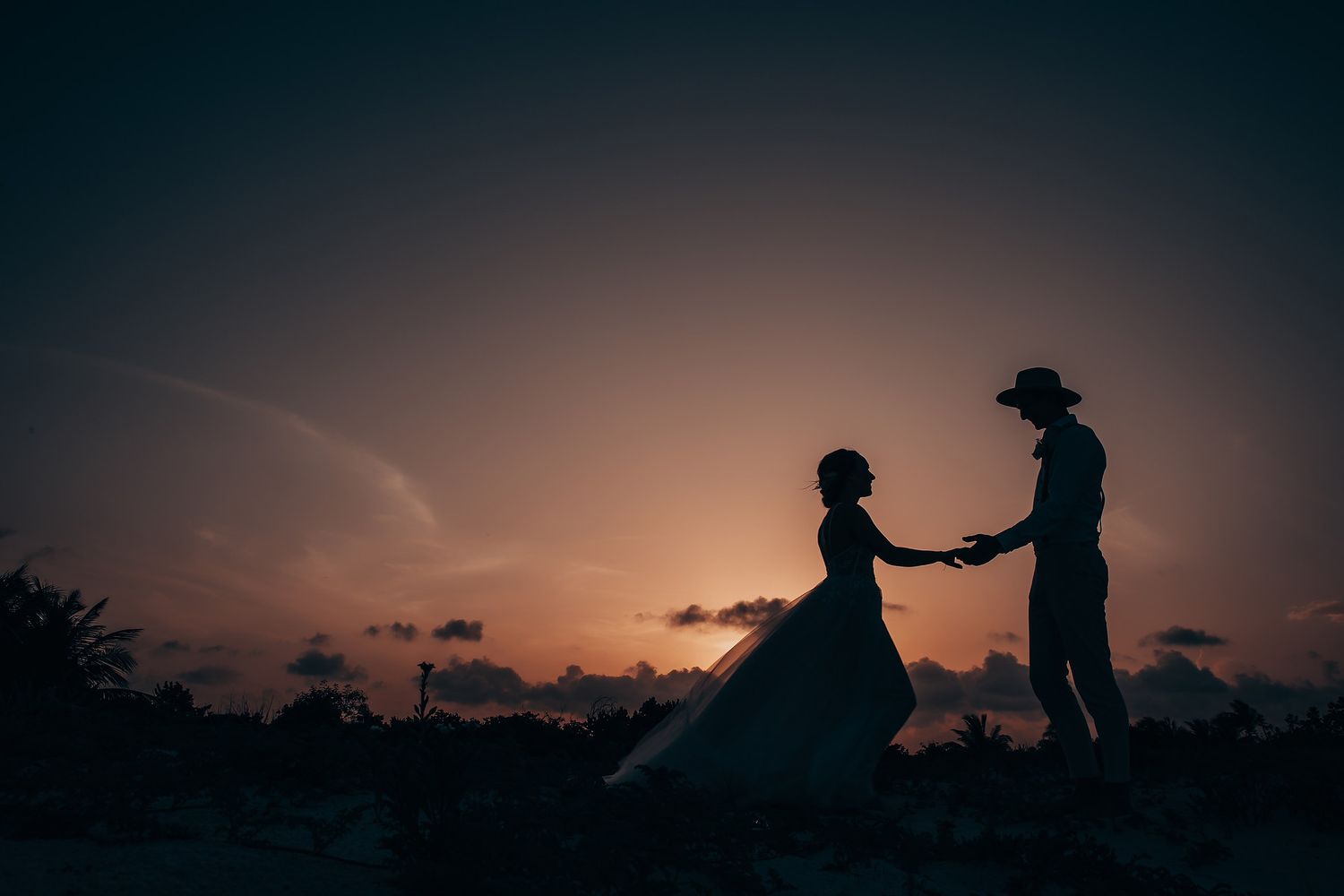 Romantic silhouette of a couple against a vibrant sunset sky.