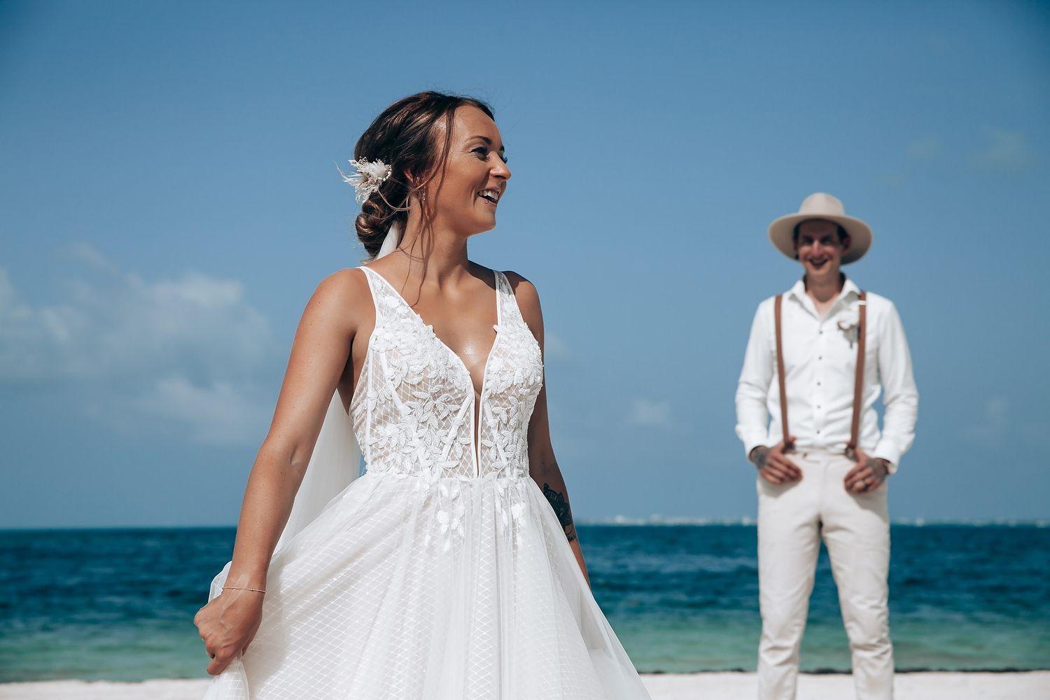Elegant beach wedding portraits featuring white dress and suit against ocean backdrop.