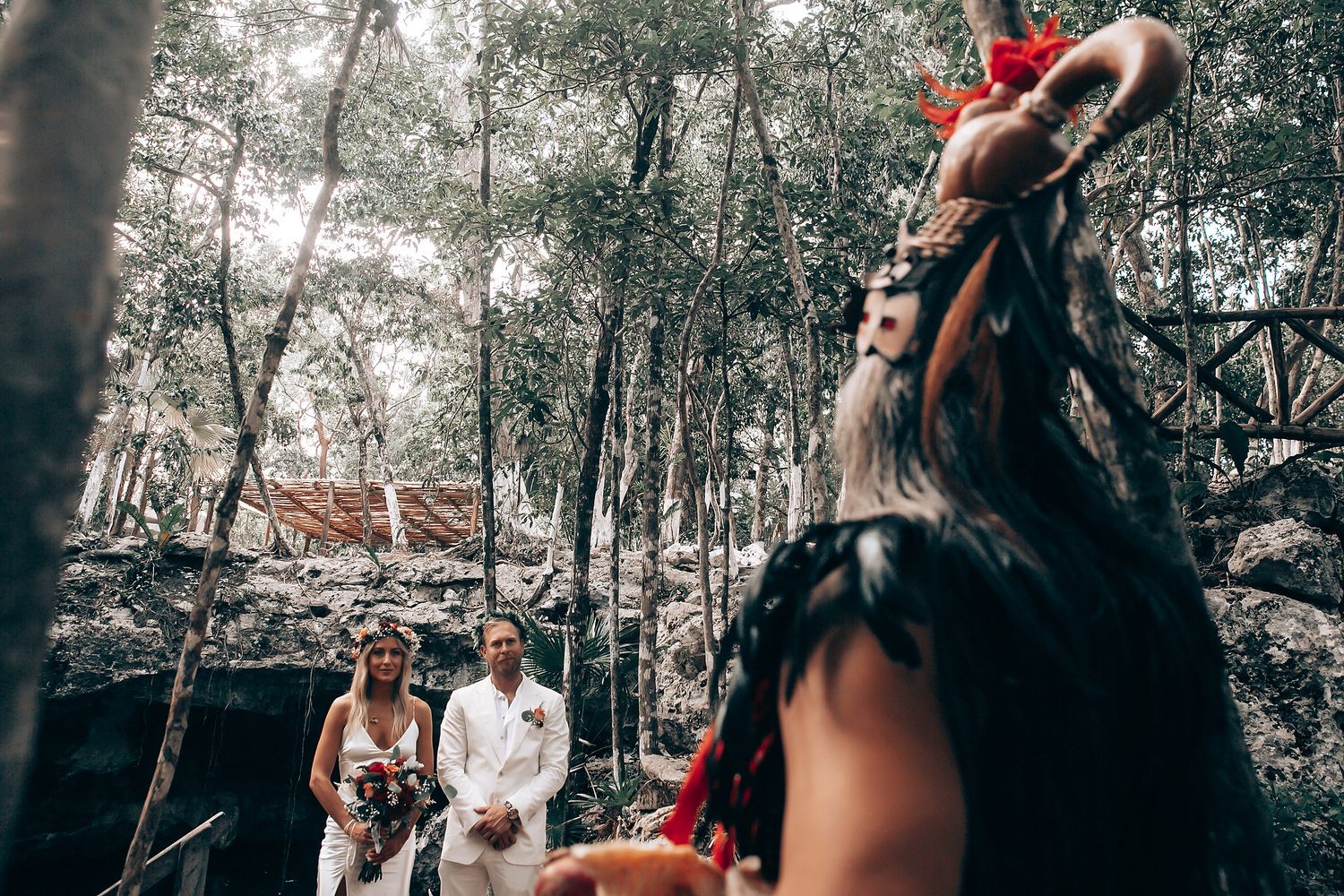 Guests celebrate during an outdoor forest wedding with natural lighting filtering through the trees.