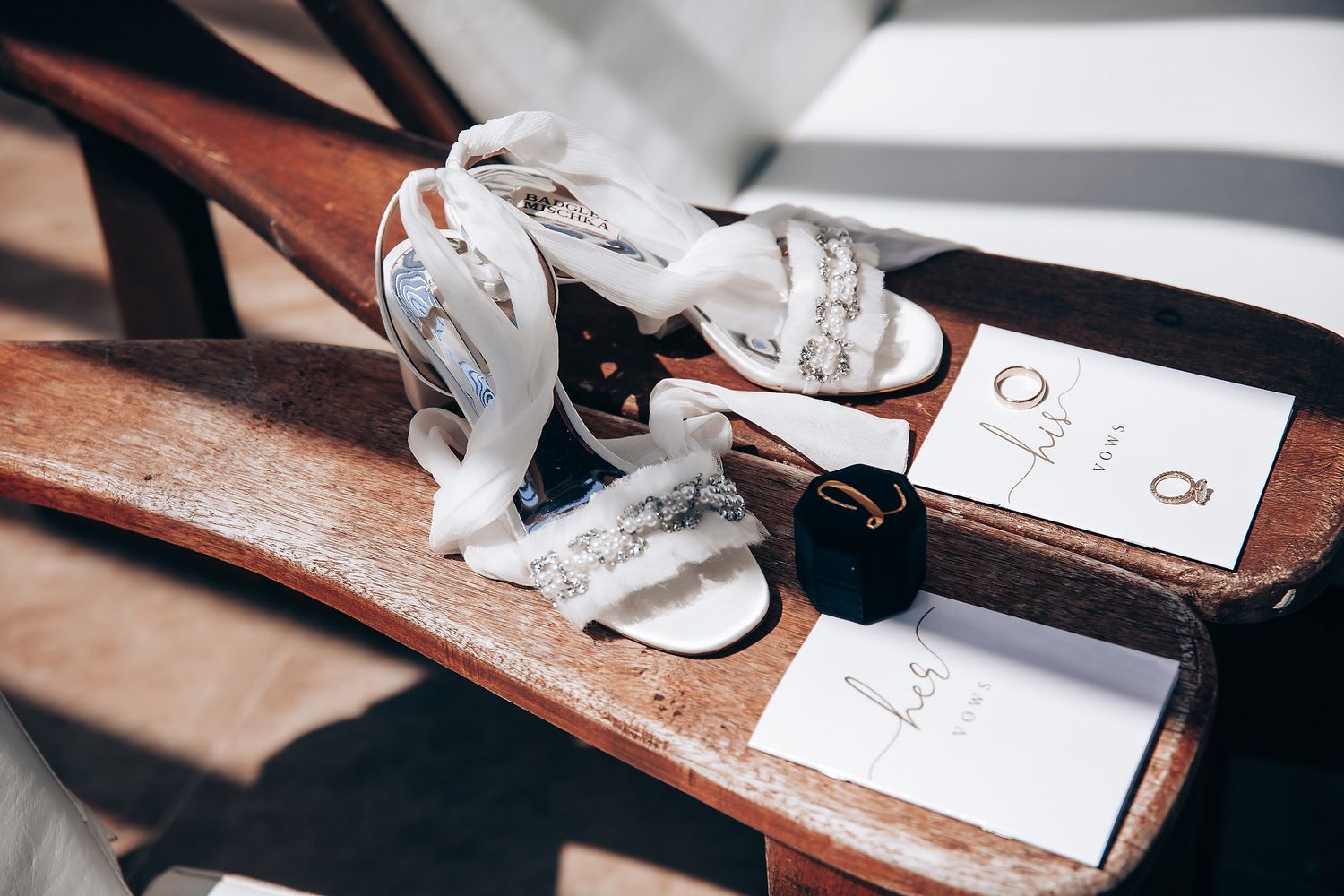 Close-up details of wedding stationery and rings arranged on a rustic wooden surface.
