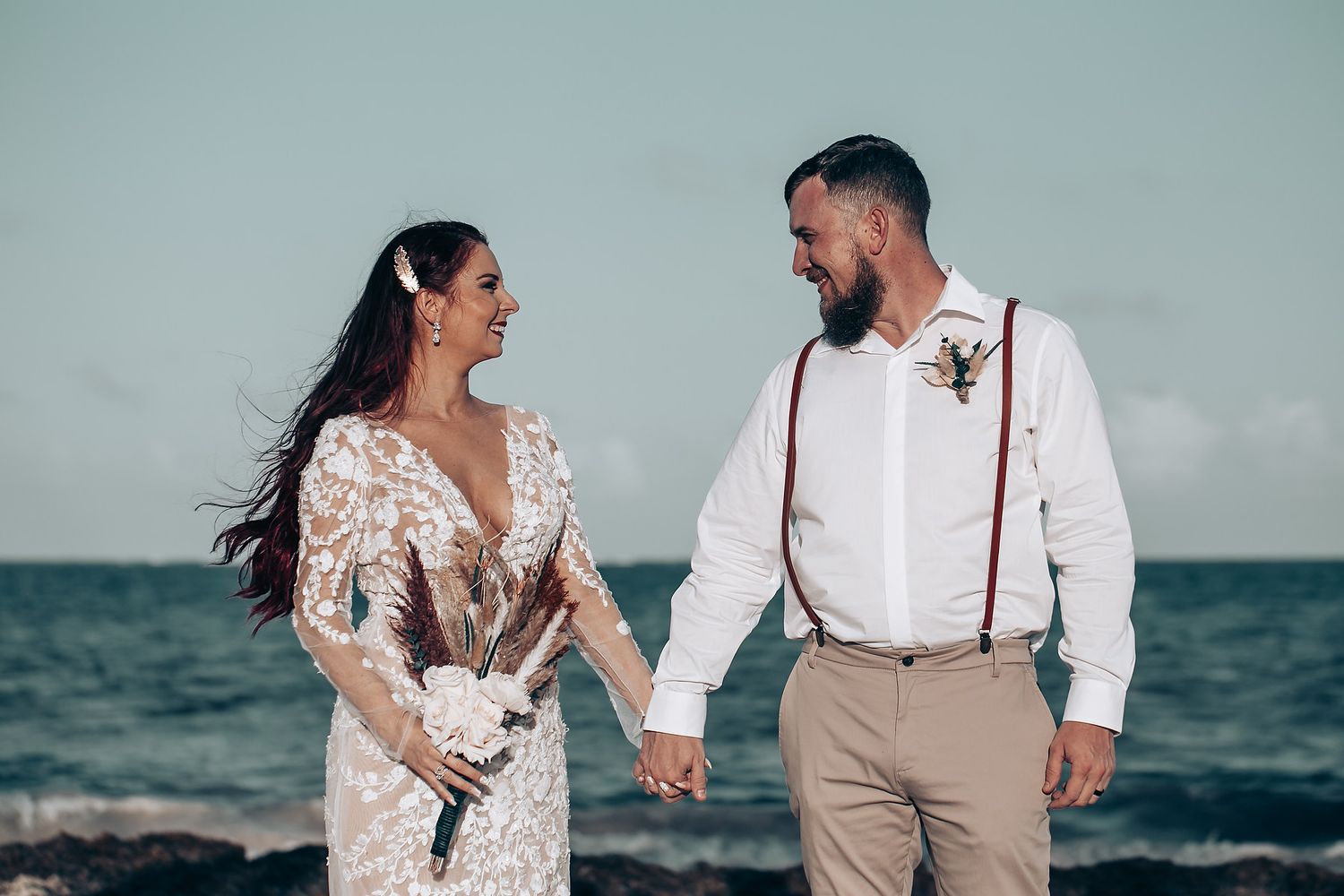 Couple poses for romantic beach wedding photos with ocean backdrop.