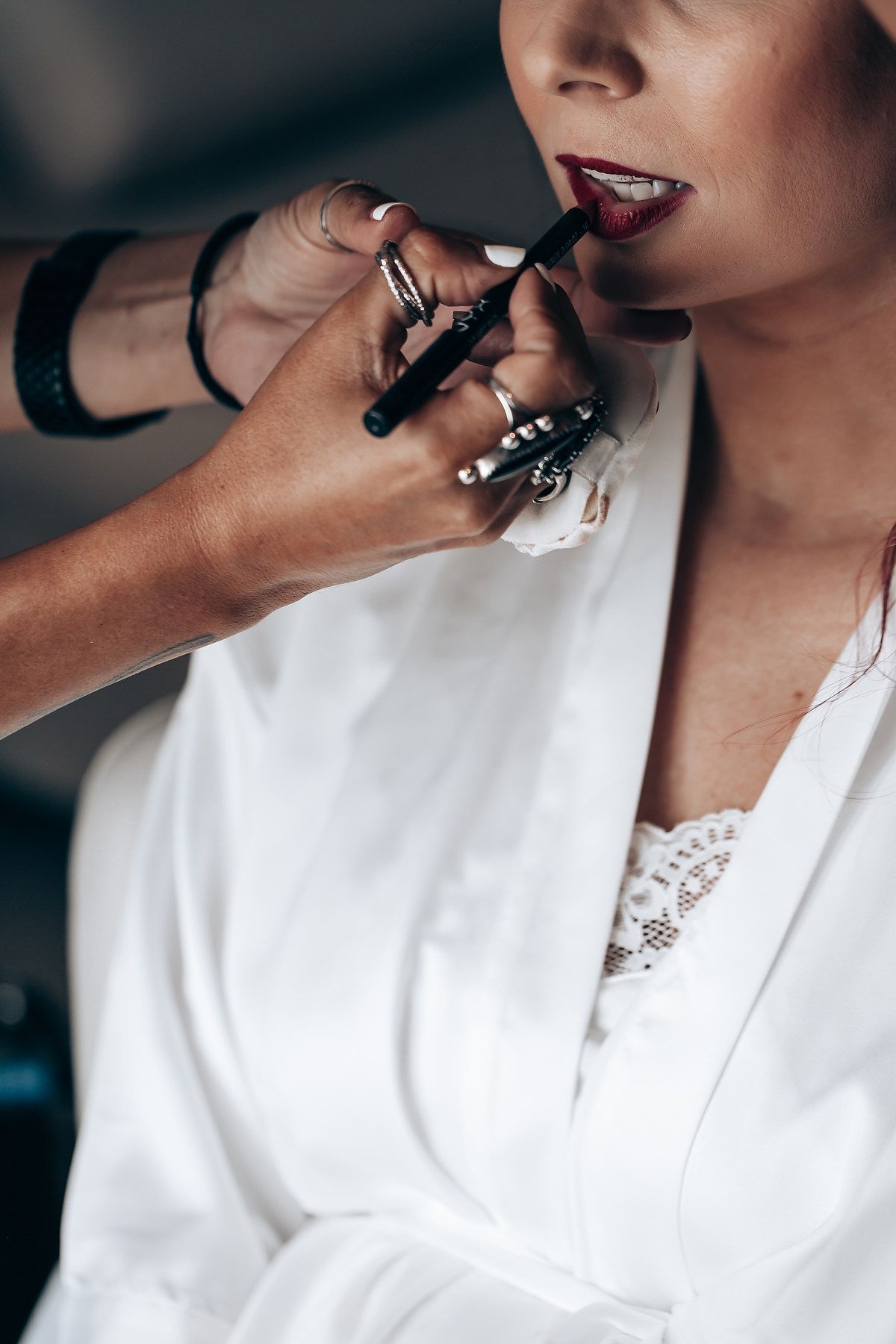A series of close-up shots showing the application of lipstick in a white robe.