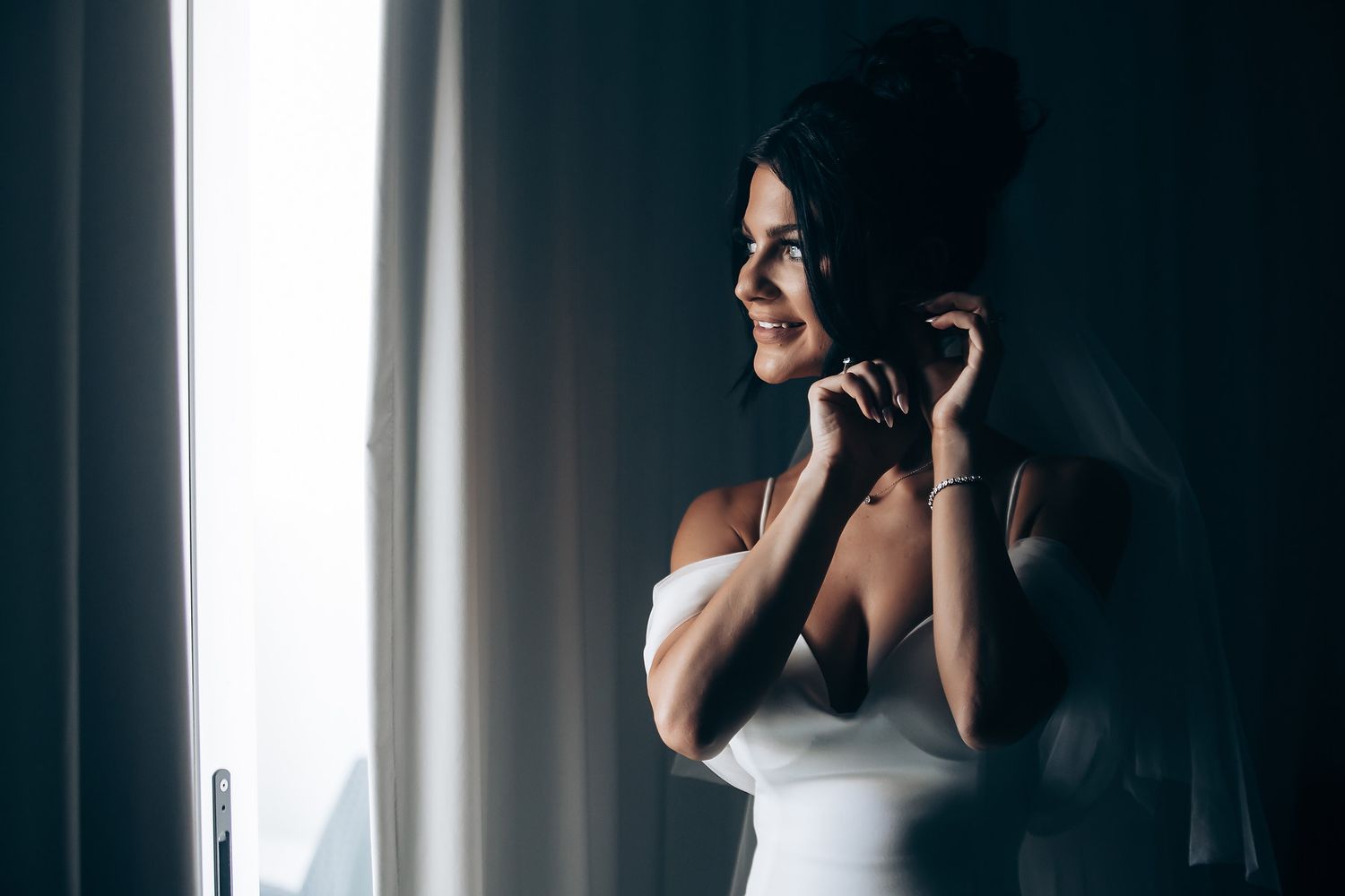 Dramatic silhouette of wedding preparations against window light.