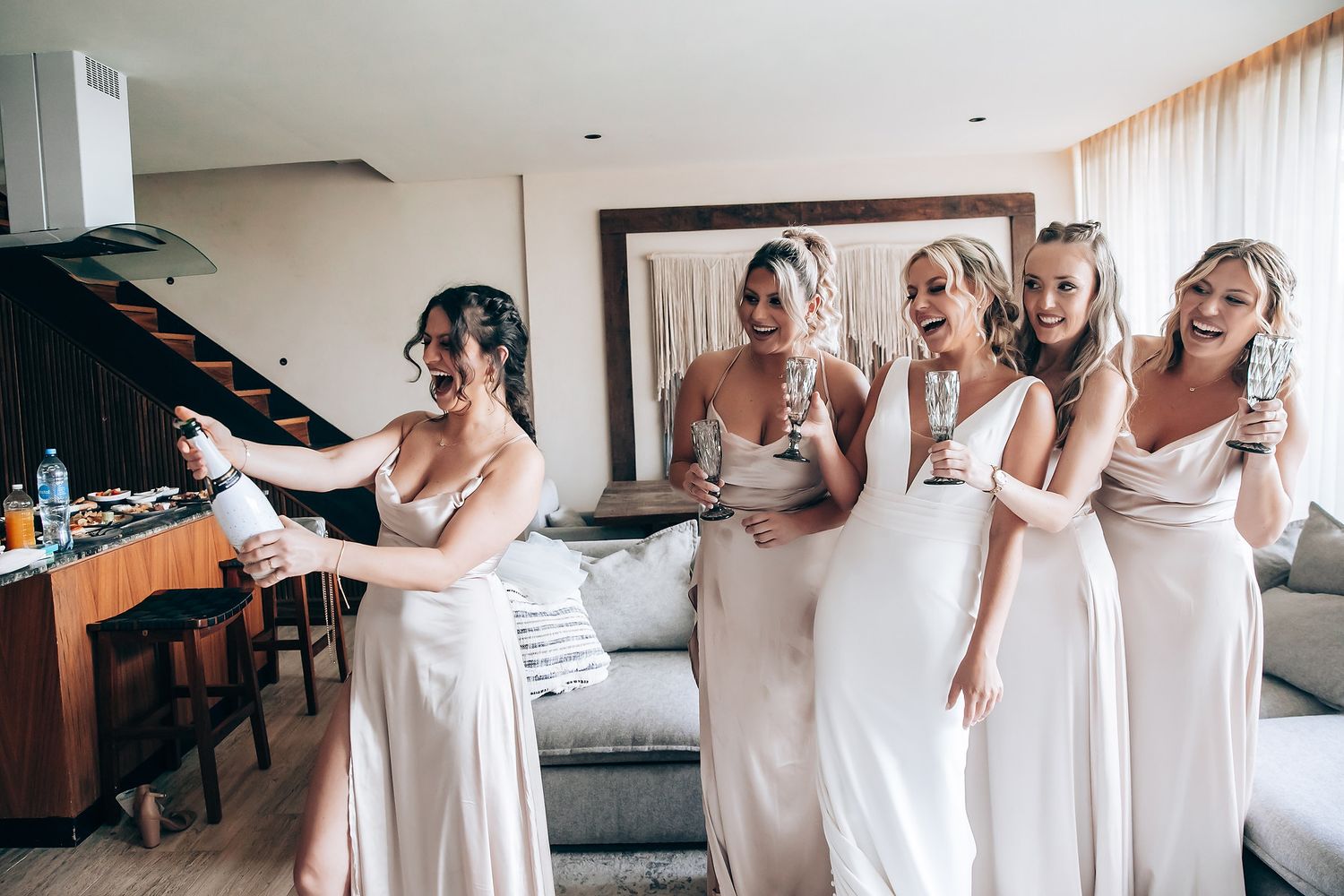 Bridesmaids in white dresses share a joyful moment together before the wedding ceremony.