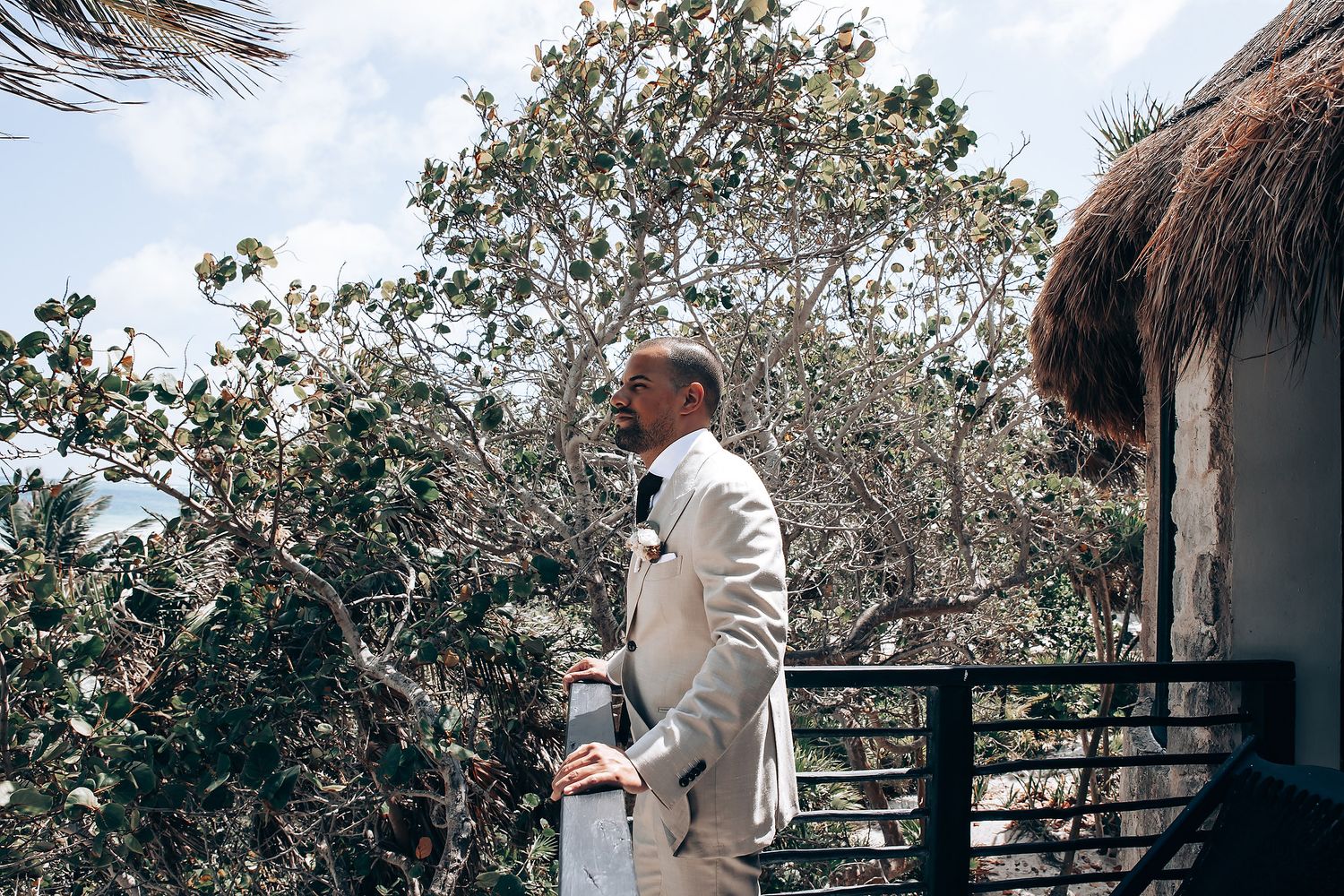 Elegant outdoor wedding venue with white decor and tropical greenery against white walls.