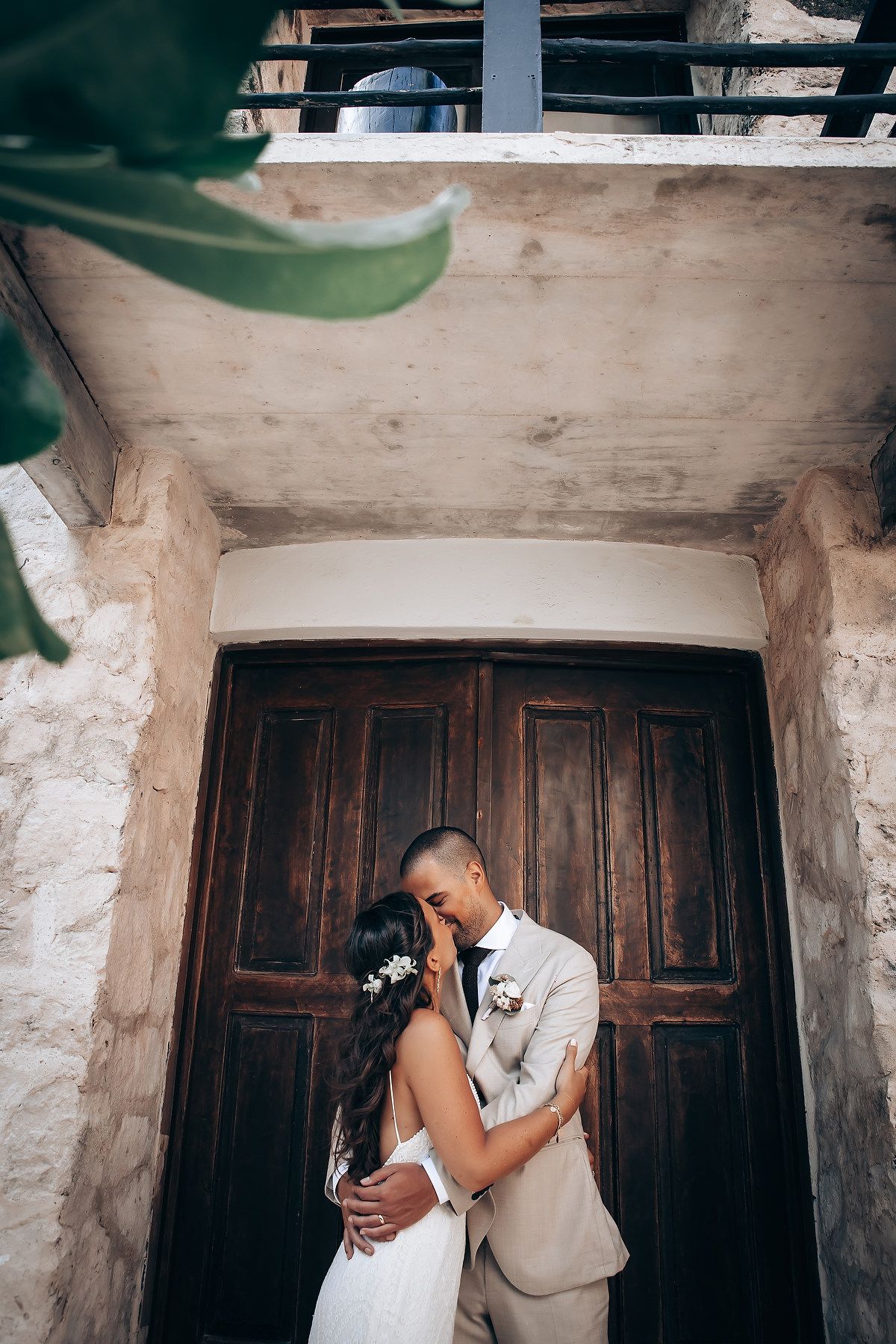 A romantic moment captured against rustic wooden doors and whitewashed walls in a vintage setting.