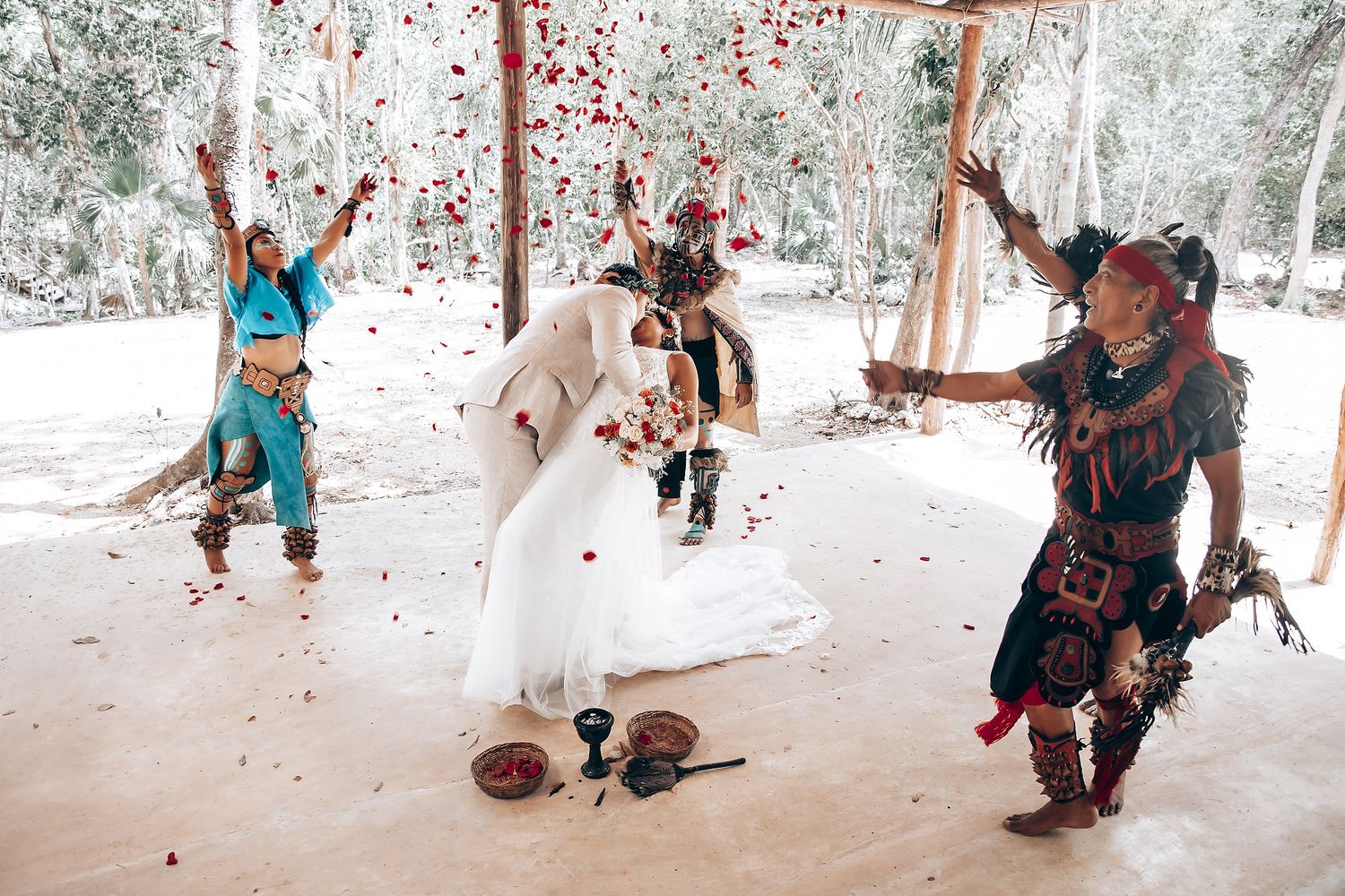 Dancers in vibrant traditional costumes perform energetic movements during an outdoor wedding celebration.