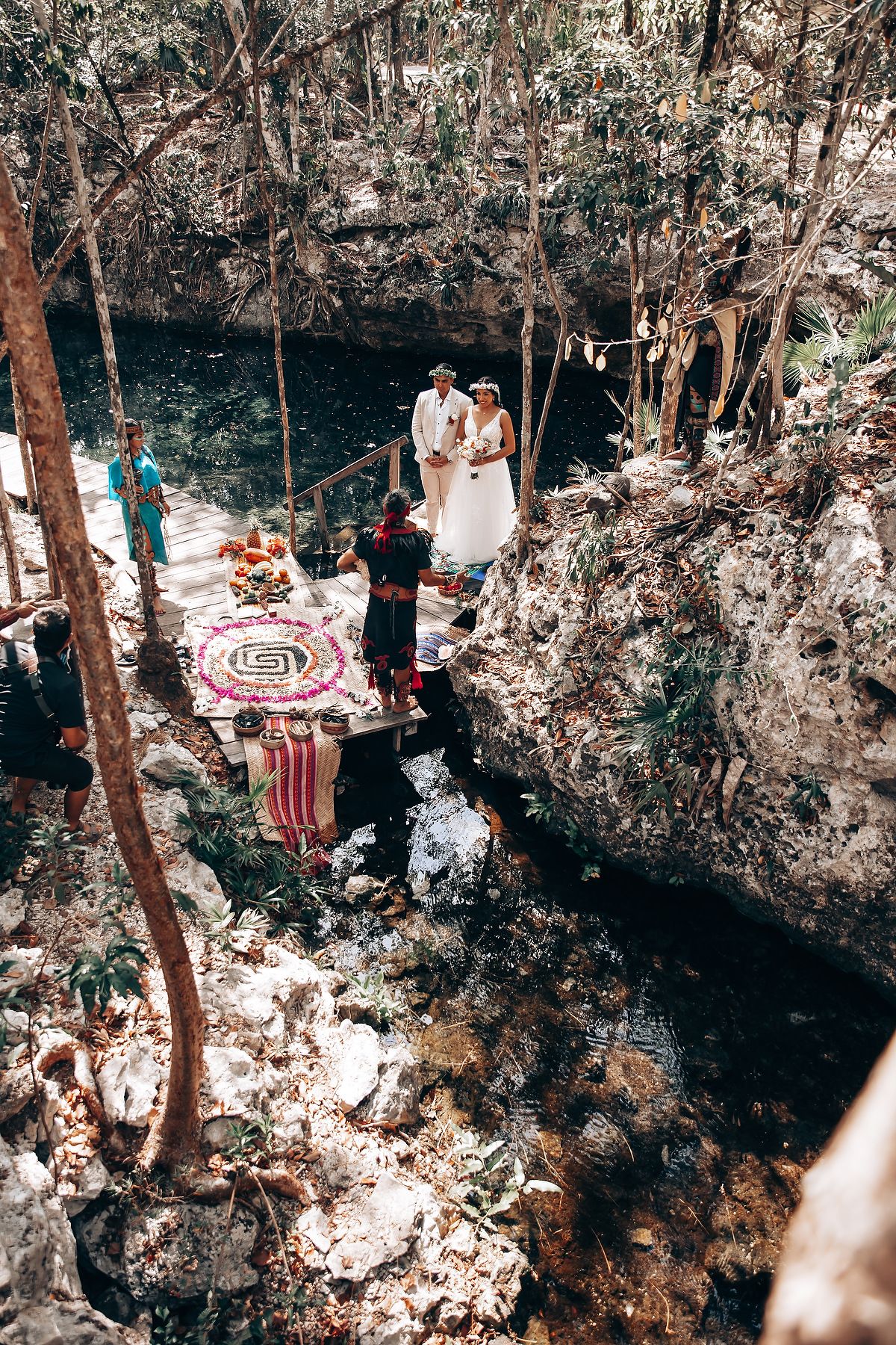 Aerial view of a wedding ceremony setup in a forest clearing with decorative elements.