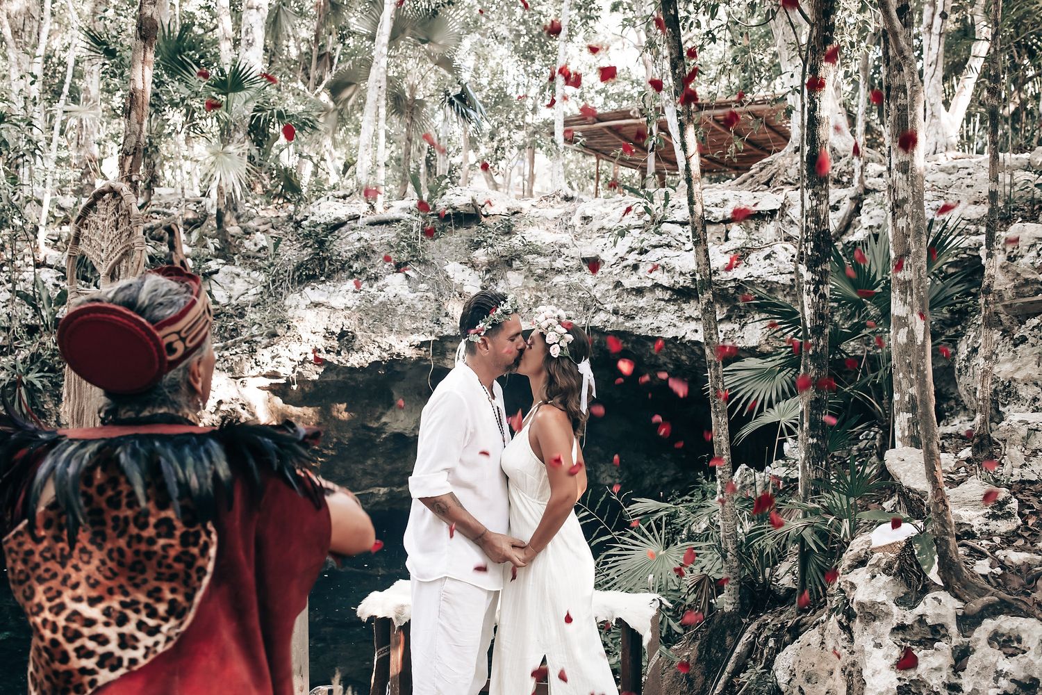 A couple walks together in a lush, forested environment, surrounded by traditional decorations.