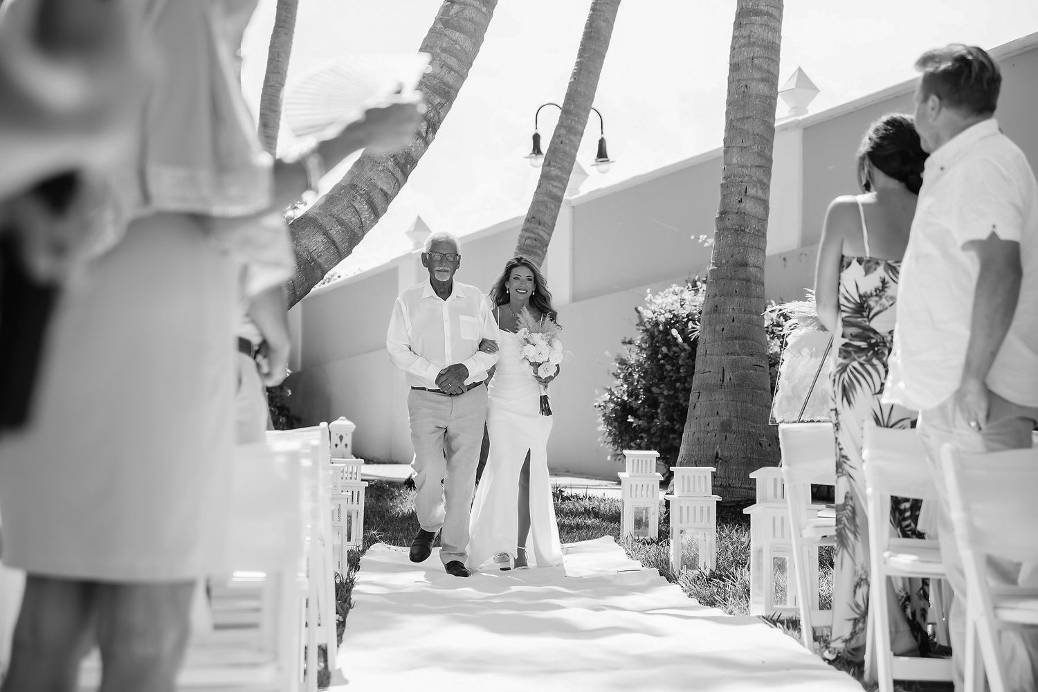 A wedding ceremony with a decorated aisle and guests in the background.