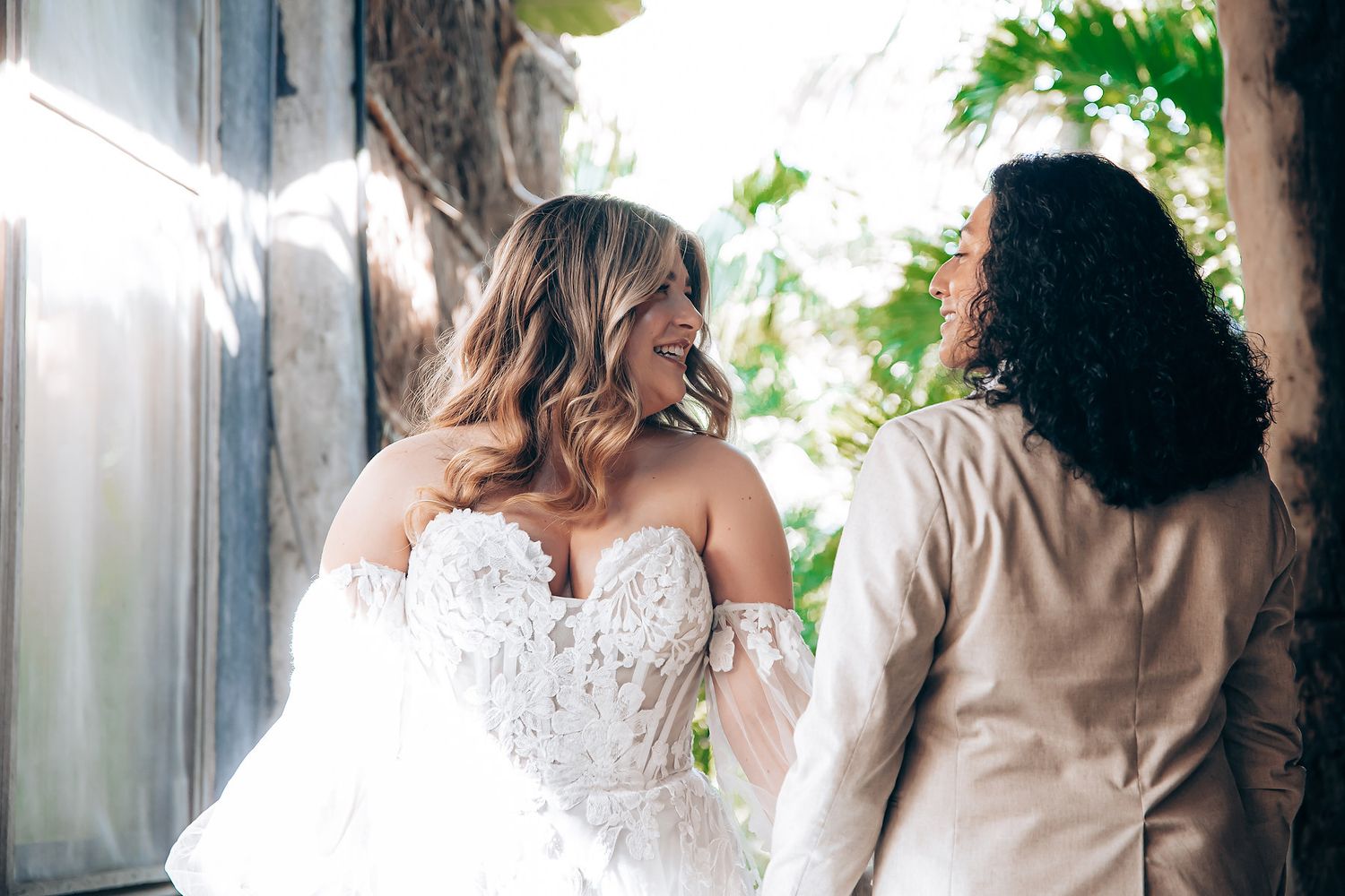 A wedding couple shares a romantic kiss under a floral arch during their outdoor ceremony.