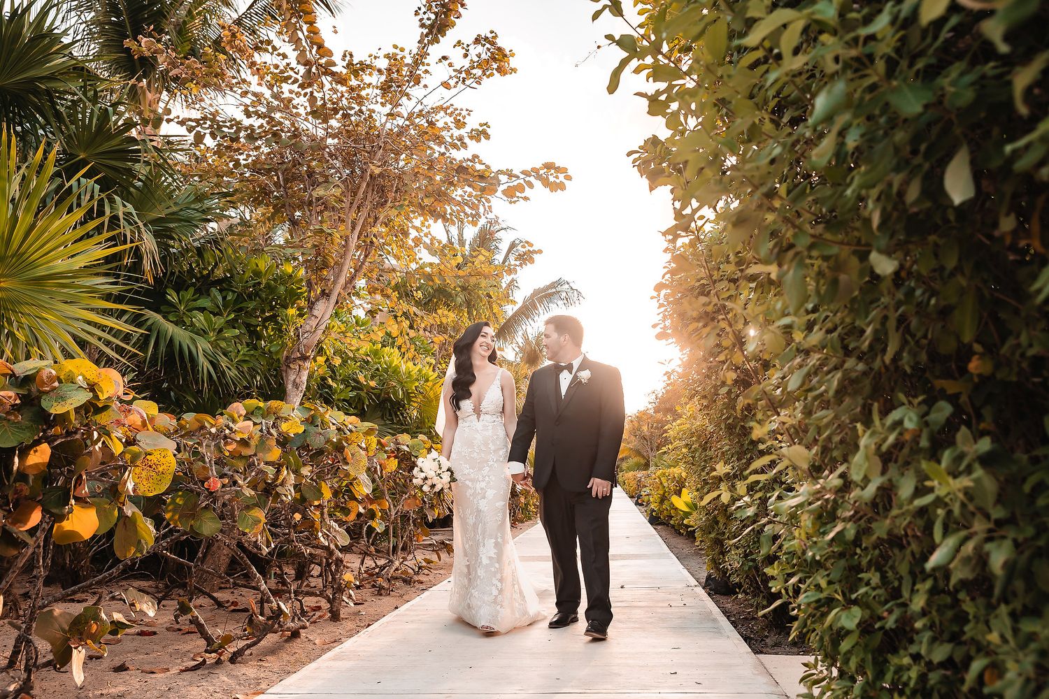 A scenic wedding path lined with lush tropical foliage at golden hour.