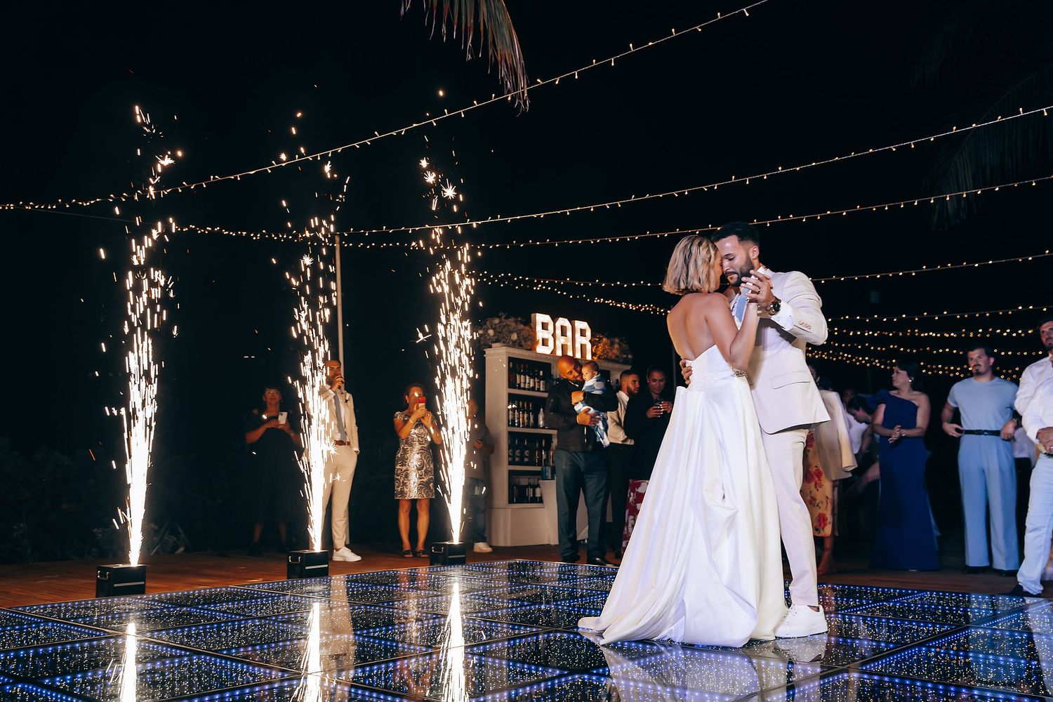 First dance moment with sparklers and LED lit floor at tropical wedding reception.