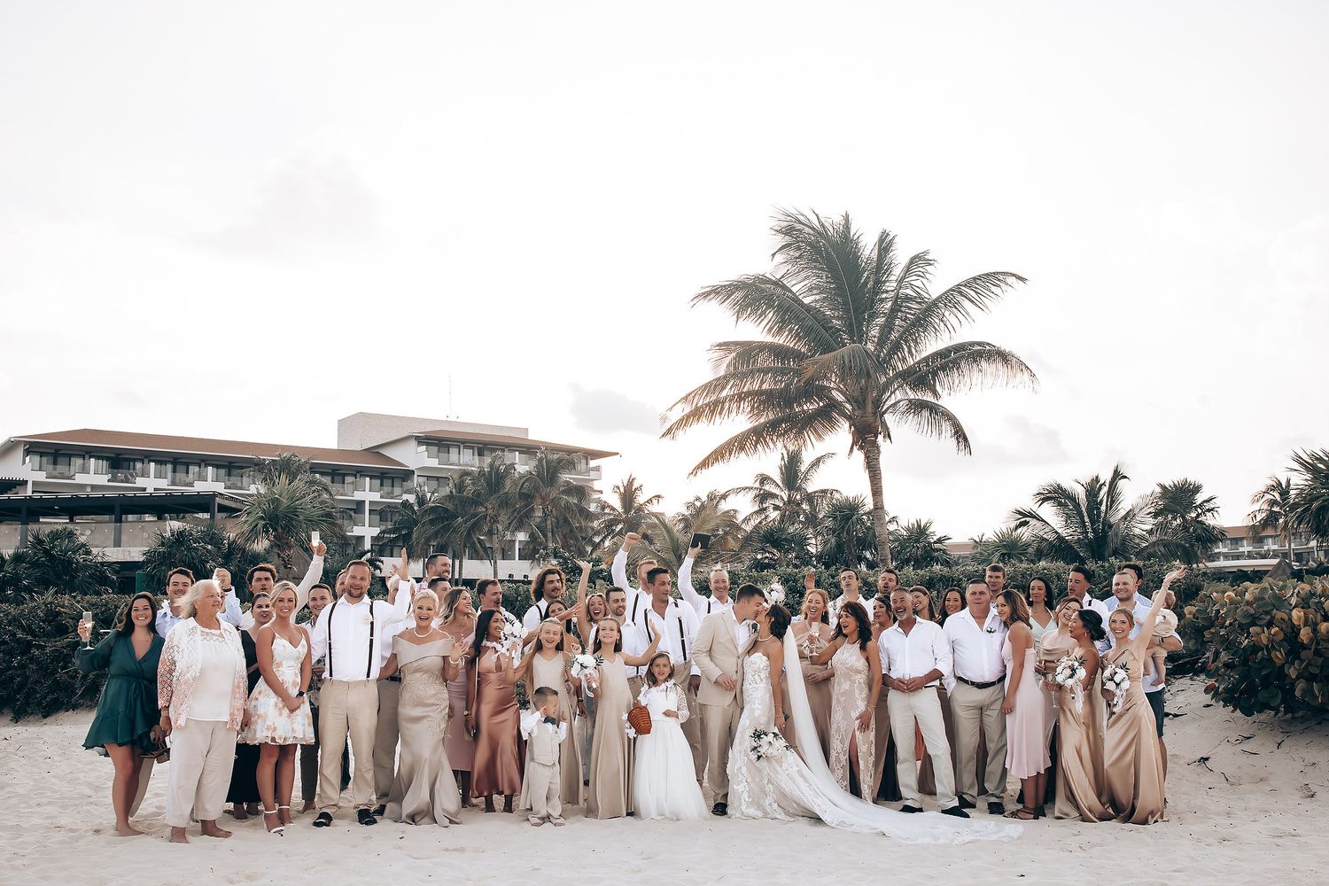 Panoramic view of a beach wedding with guests in neutral colors against a tropical backdrop.