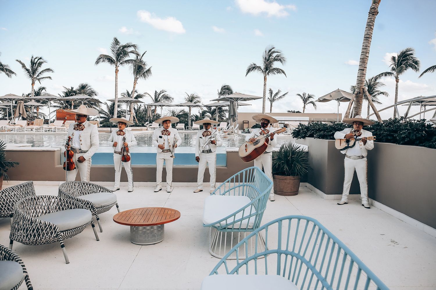 Elegant outdoor wedding venue with white decor, palm trees and ocean views at a tropical resort.