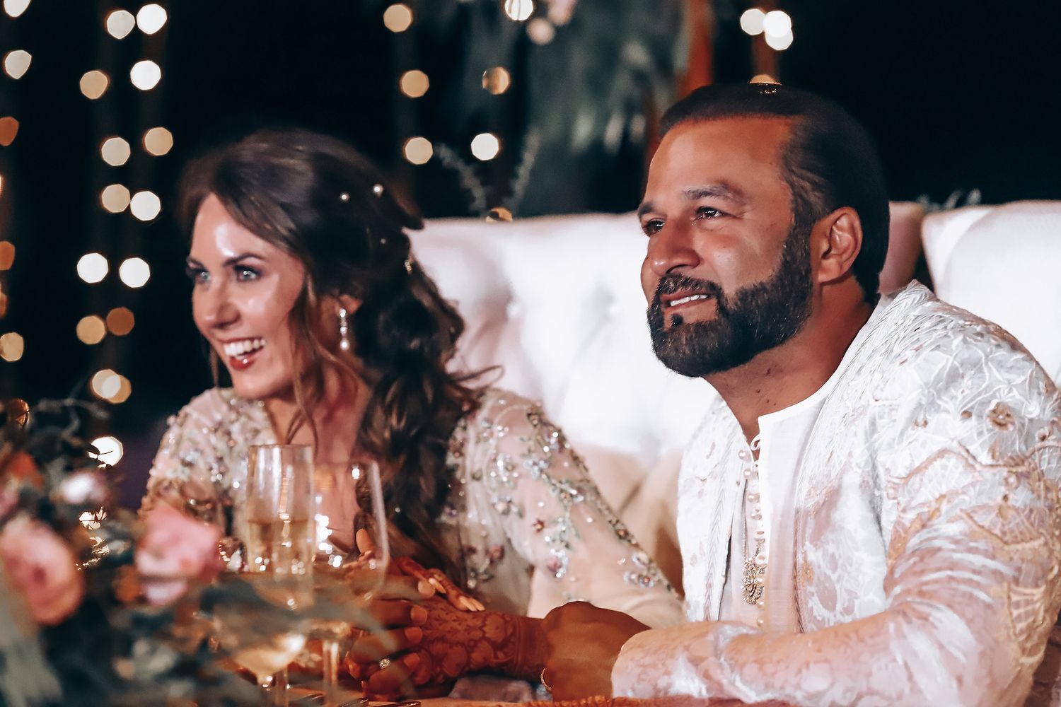 A wedding celebration with guests seated at a candlelit table enjoying an elegant dinner party.