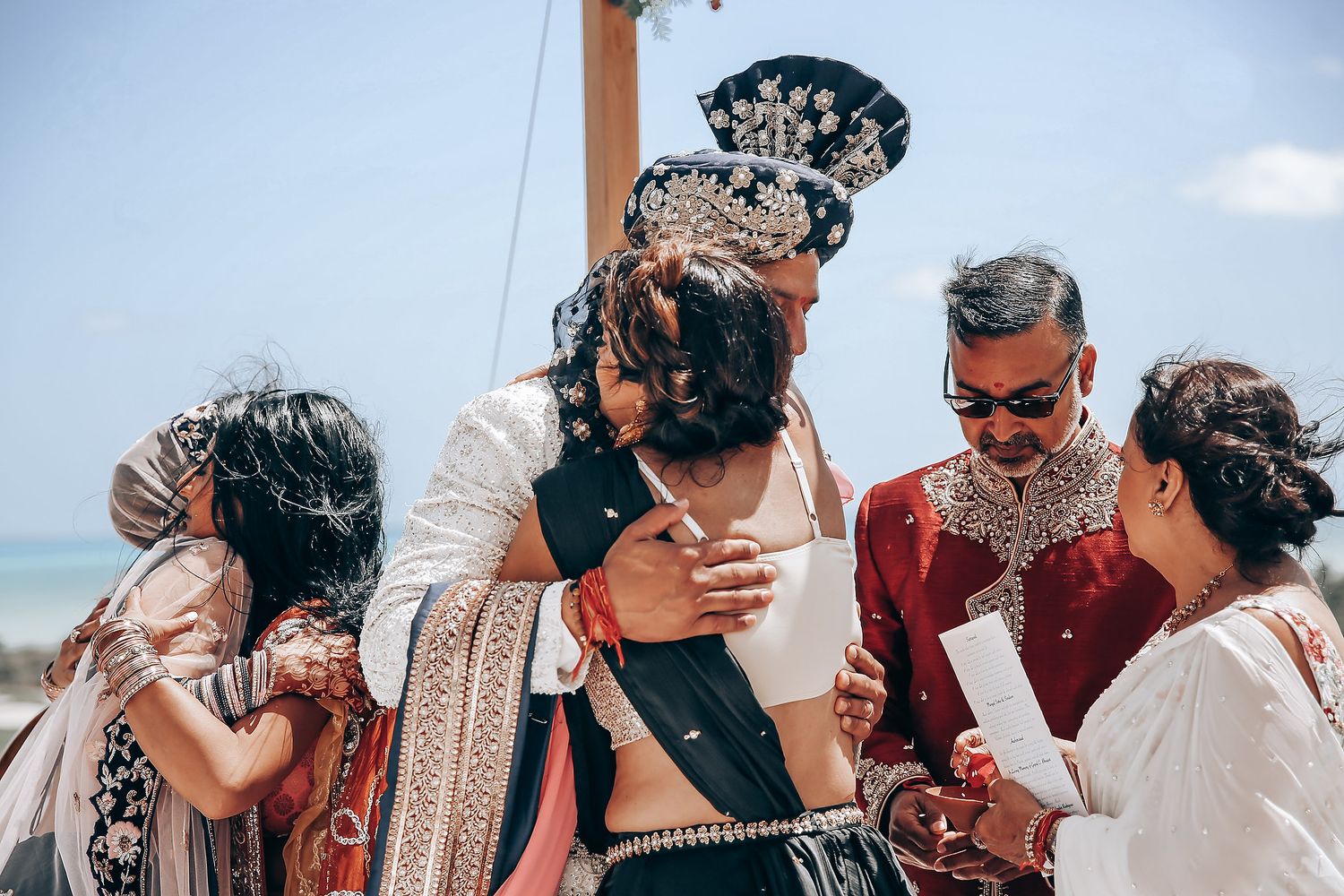 Wedding guests celebrate outdoors with confetti and joyful expressions during a beach ceremony.