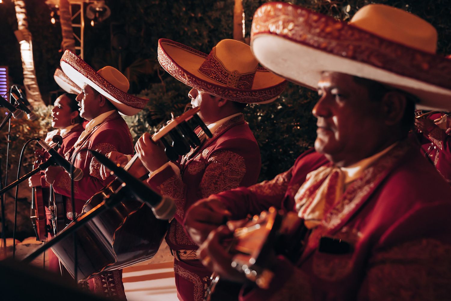 Traditional mariachi band performs in colorful outfits and sombreros under evening lights.