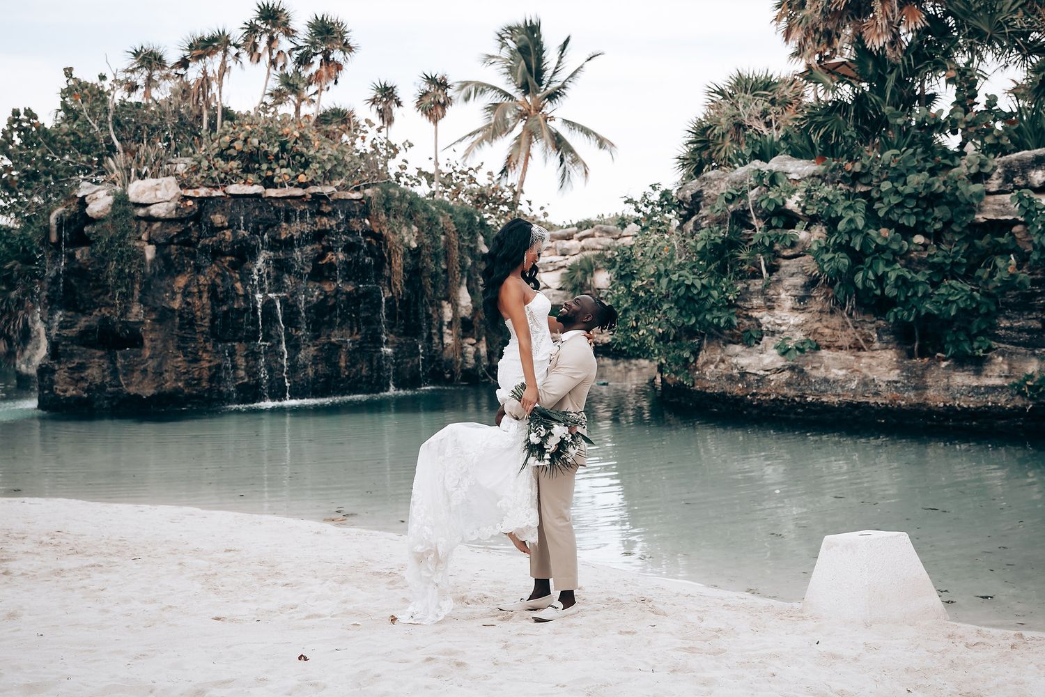 Tropical wedding venue with stone walls and palm trees overlooking crystal blue waters.