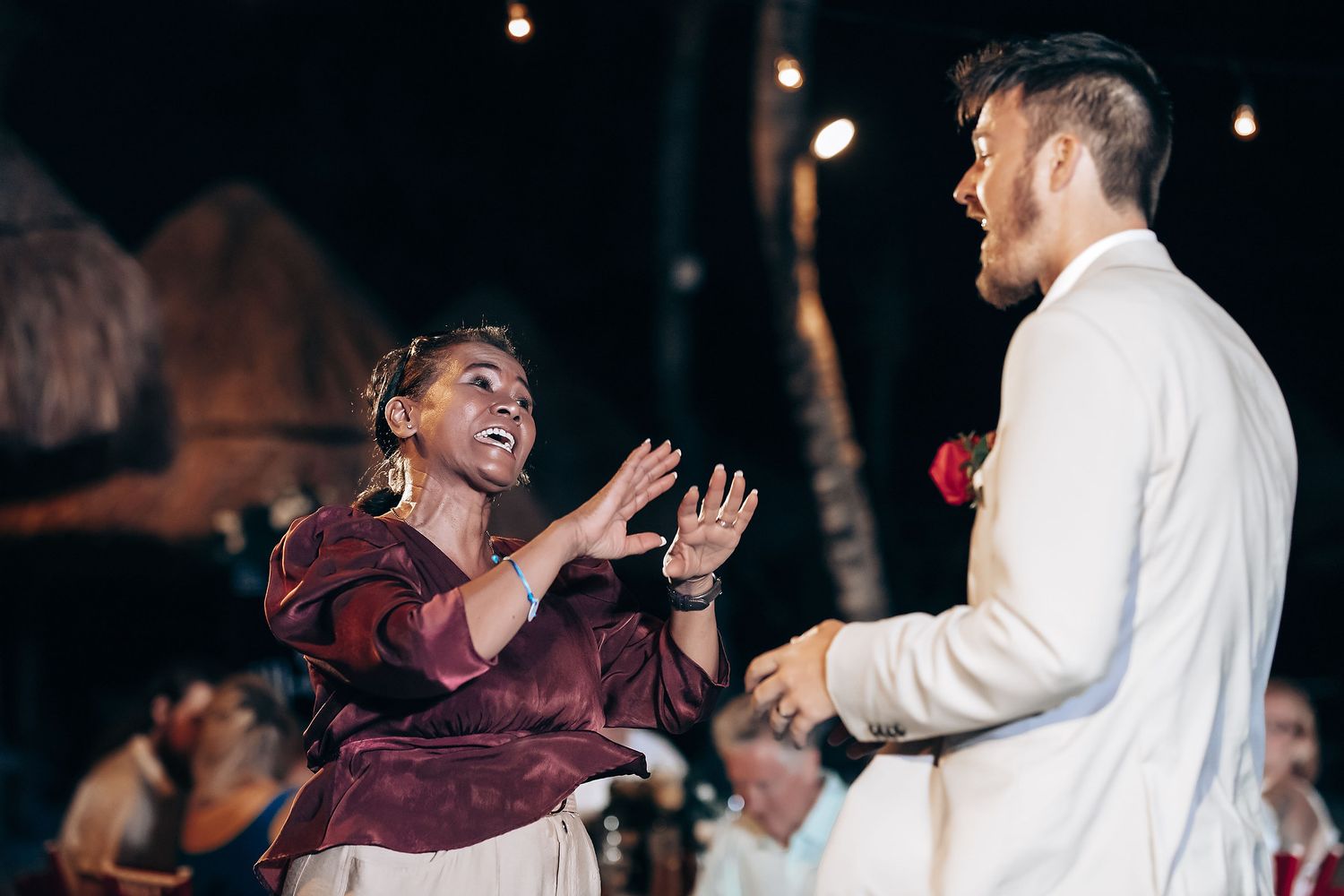 Wedding guests dancing and celebrating during nighttime reception.