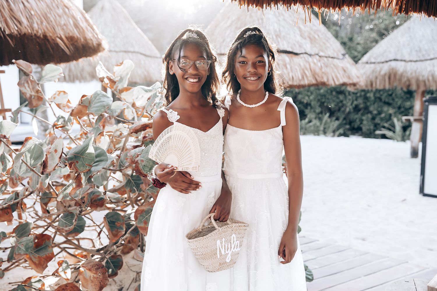 Wedding celebration on a white sandy beach with tropical decor and palm frond umbrellas.