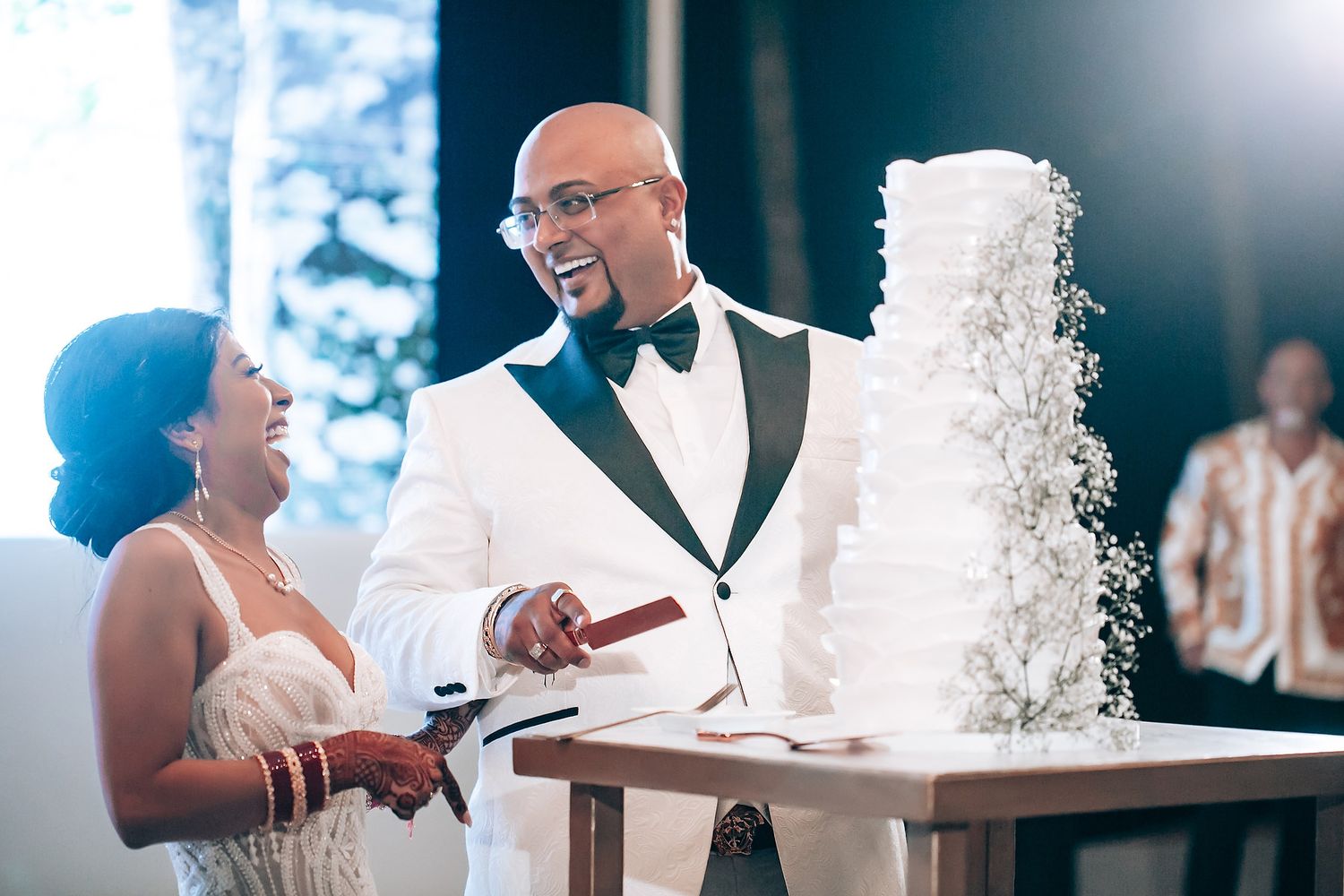 A couple cutting their elegant white wedding cake together during their reception celebration.