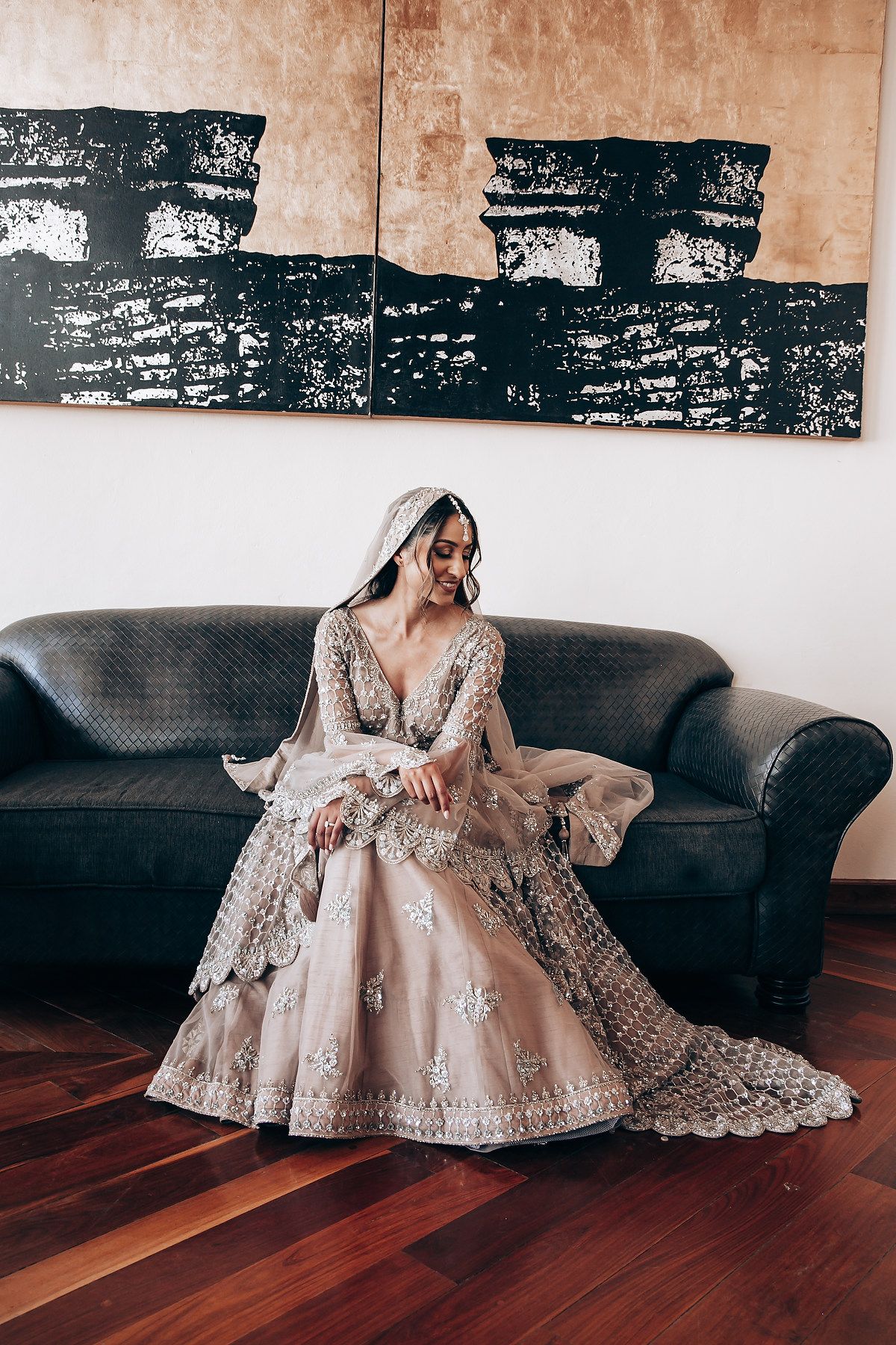 Luxurious wedding dress with intricate beadwork spread across a leather couch.